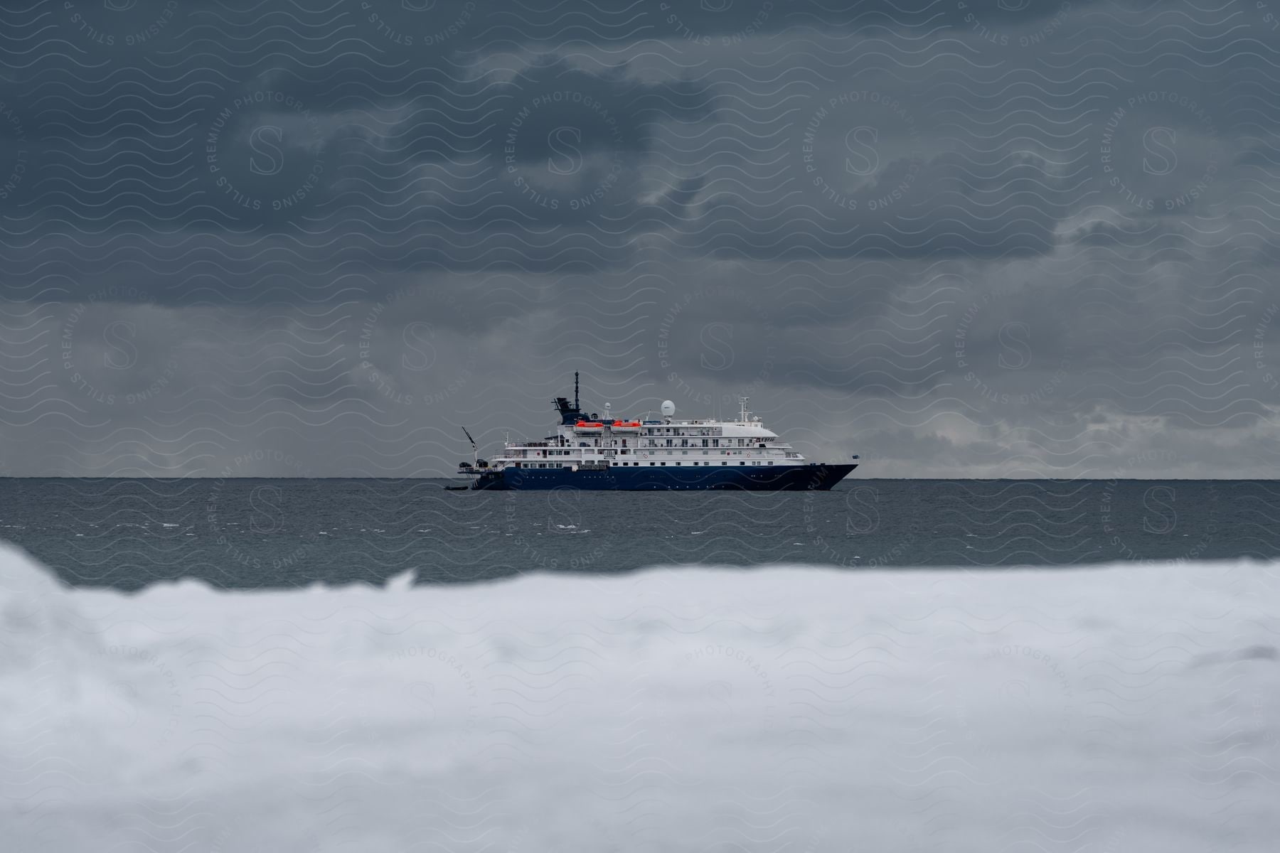 Cruise ship sailing off the arctic coast under a dark cloudy sky