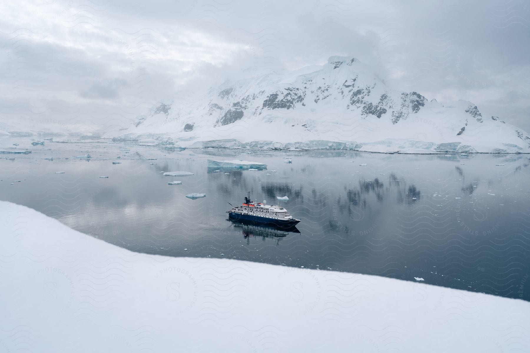 Ship anchored in bay in front of snow covered mountain