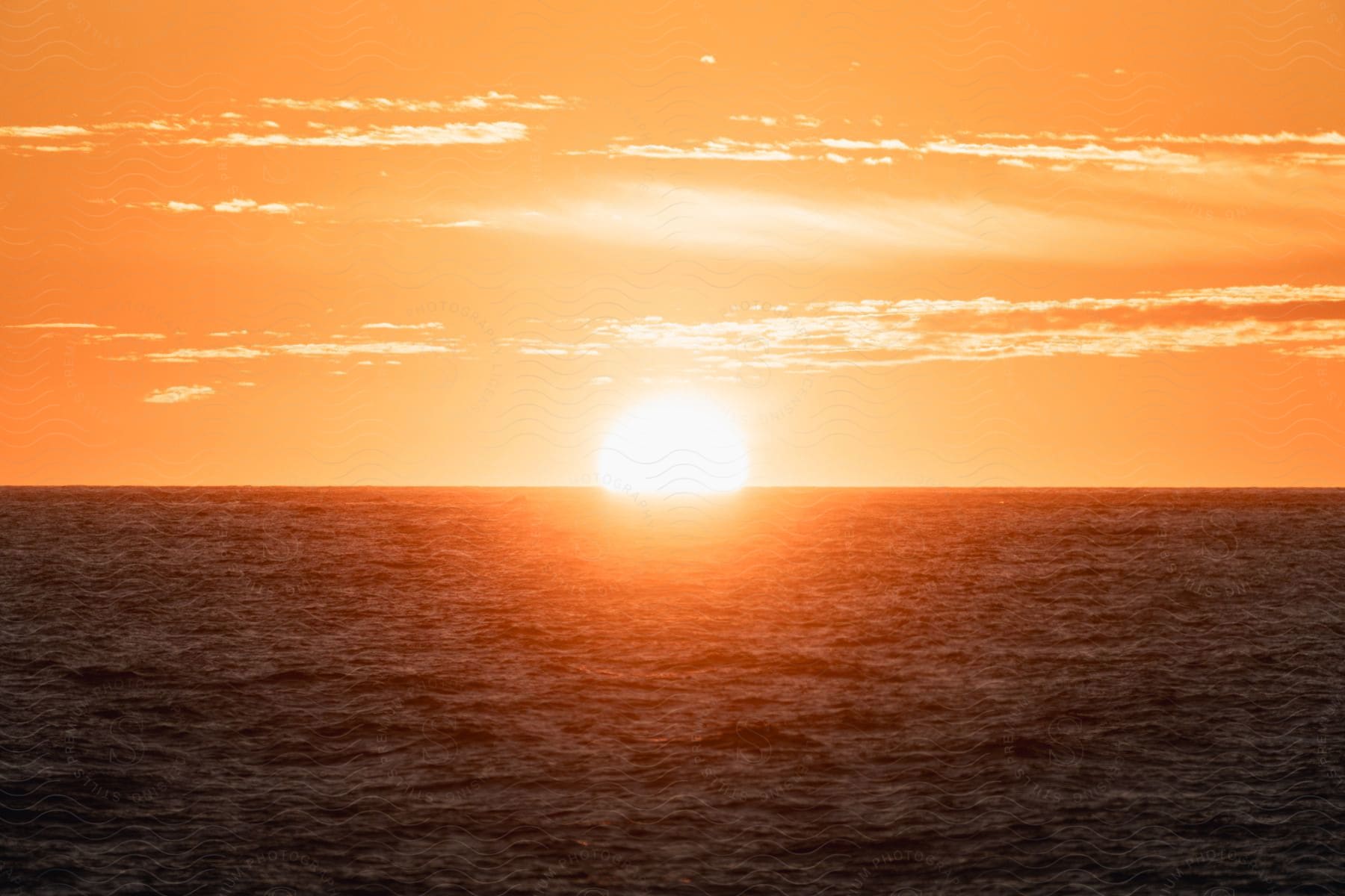 Ocean landscape with sunrise on the horizon in an orange sky