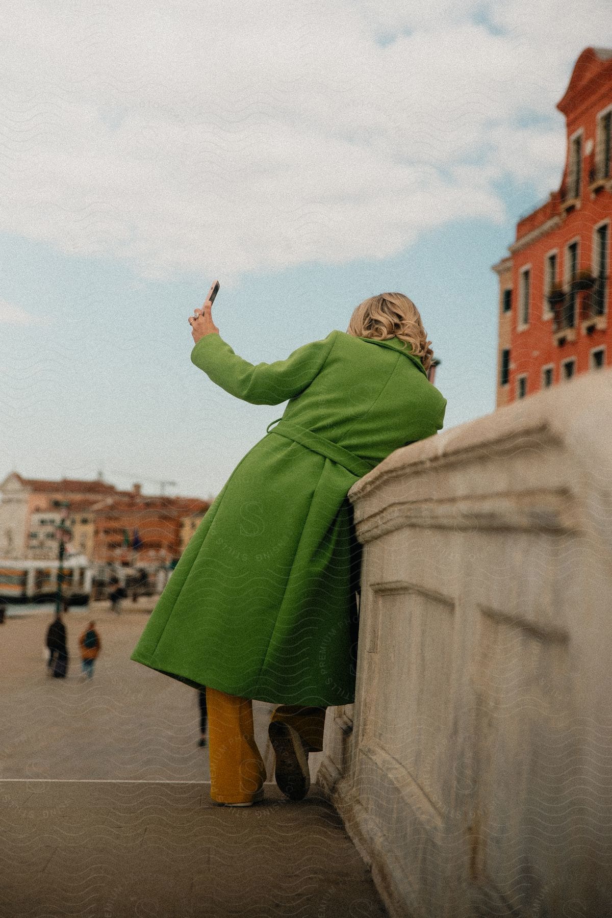 Tourist wearing green coat takes selfie on cloudy day