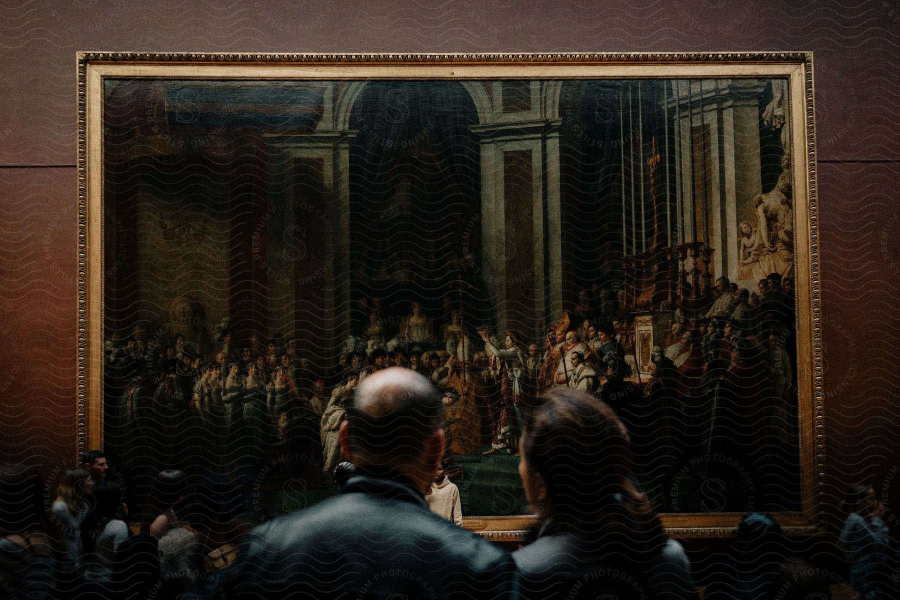 People at a museum looking at a large painting of a coronation.