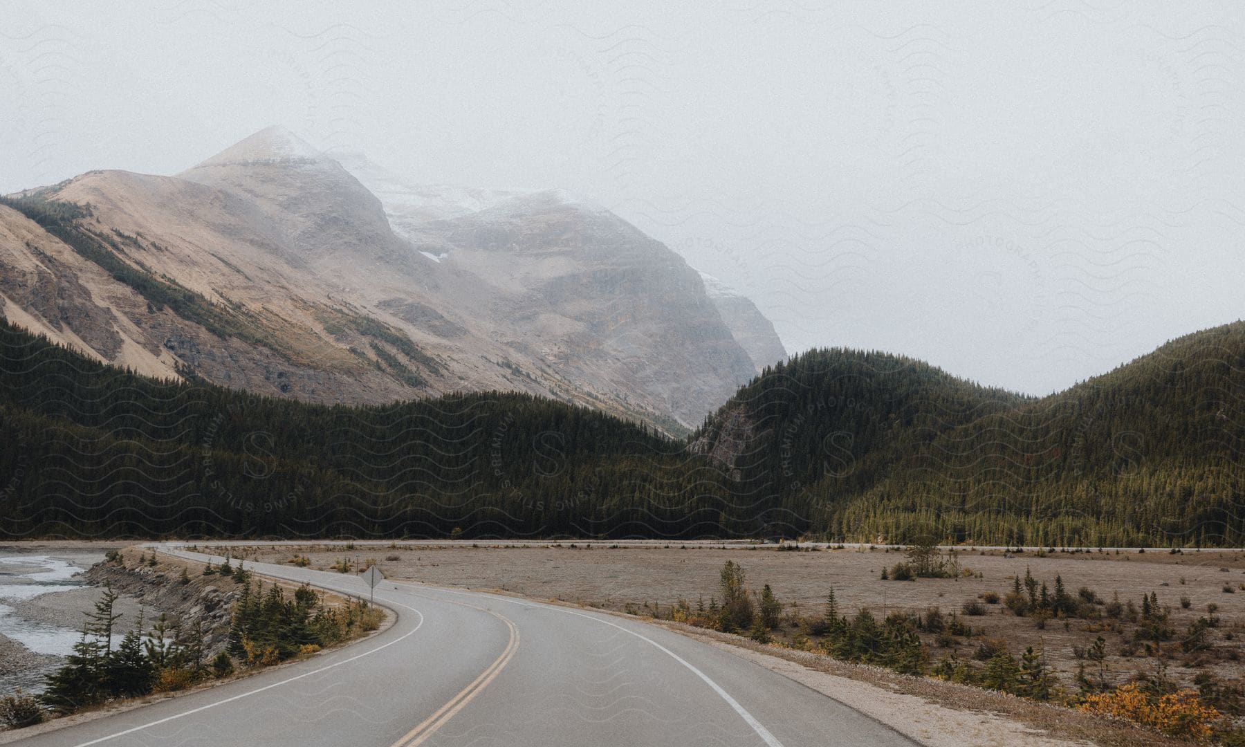 A highway winds toward the mountains and tree covered hills of Banff National park