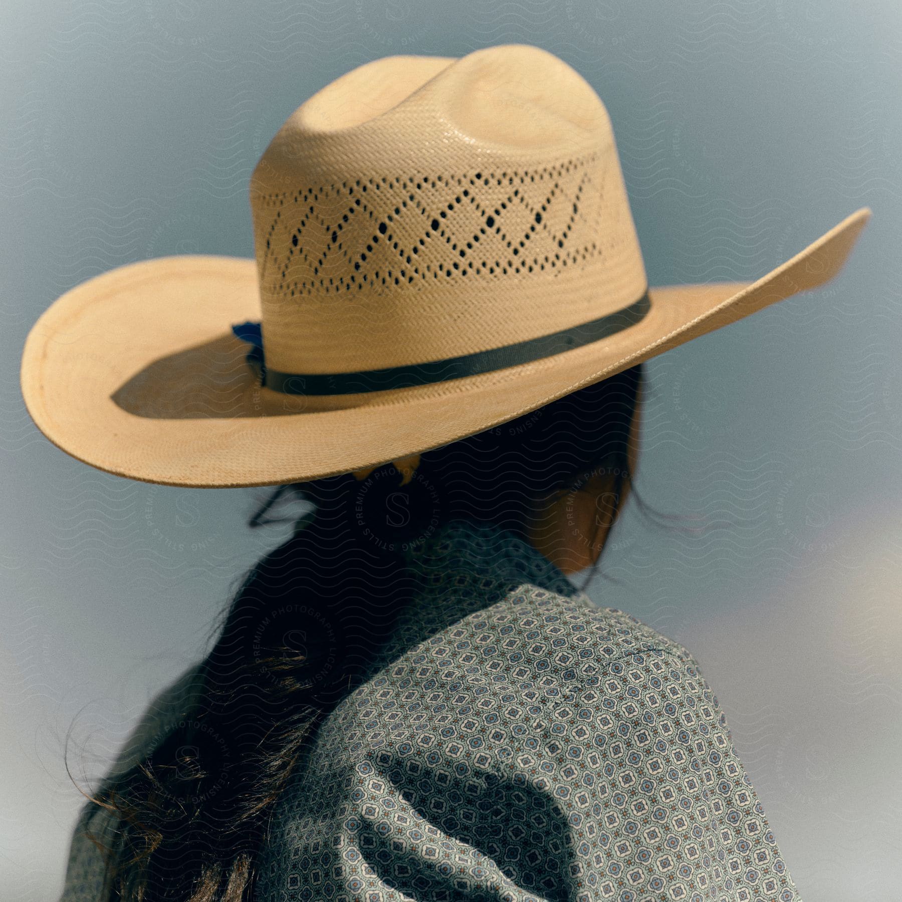A woman is wearing a wide-brimmed sun hat and a textured shirt