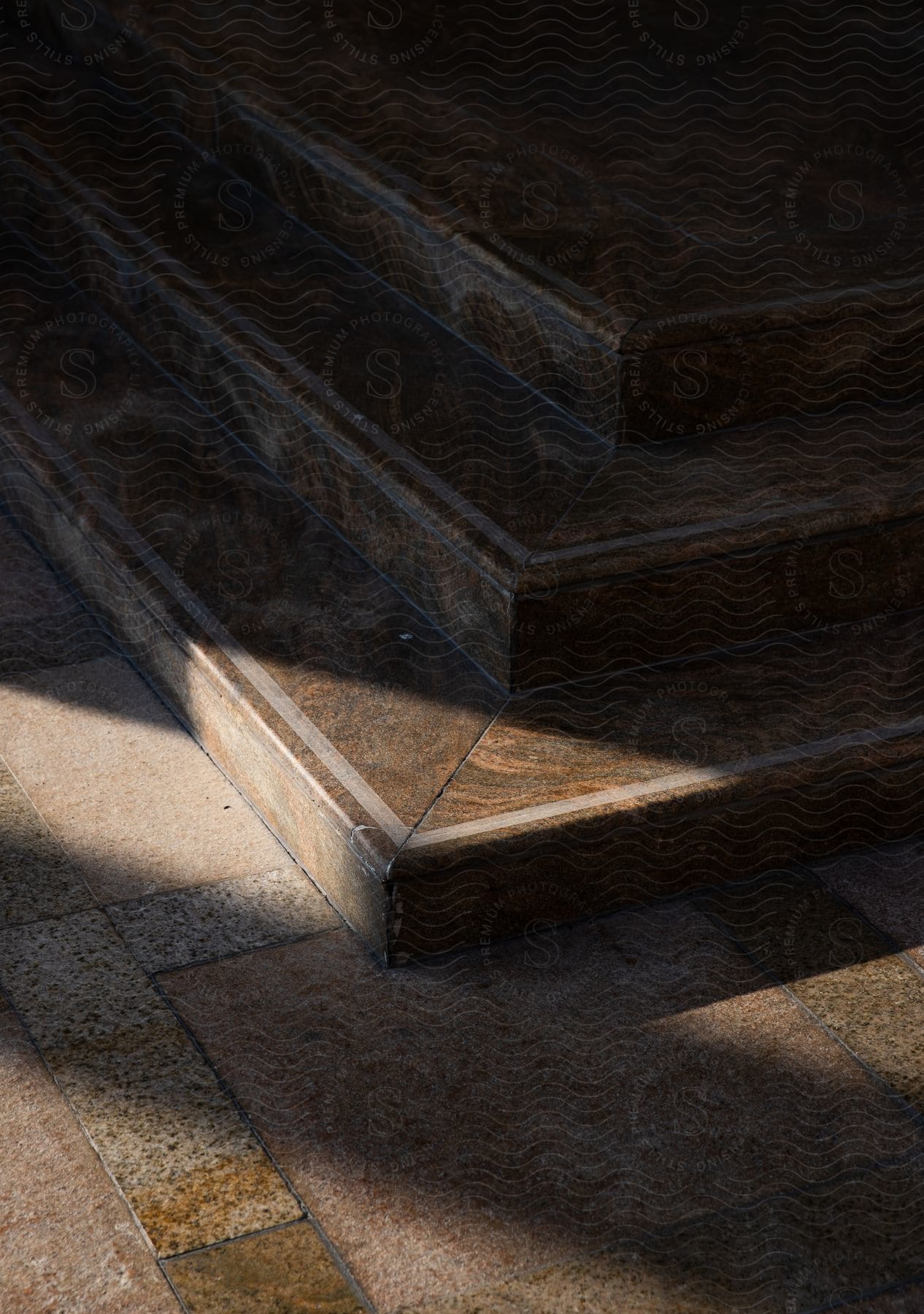 Staircase architecture with three marble steps and the reflection of natural sunlight