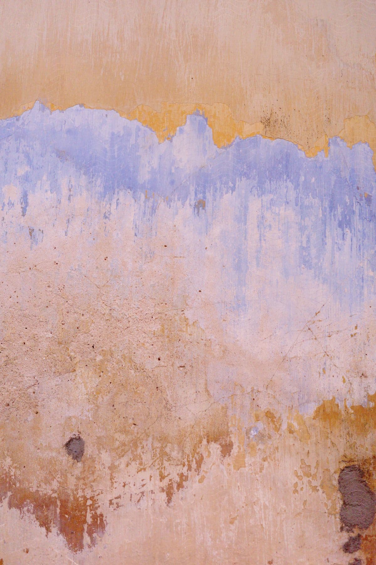 Weathered wall with peeling blue and yellow paint showing exposed textures