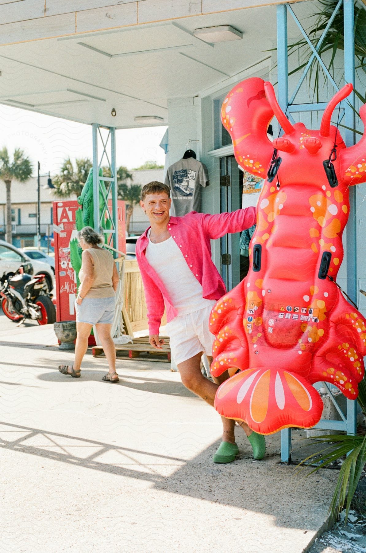 A man with a smiling face is posing next to a large colorful inflatable lobster.