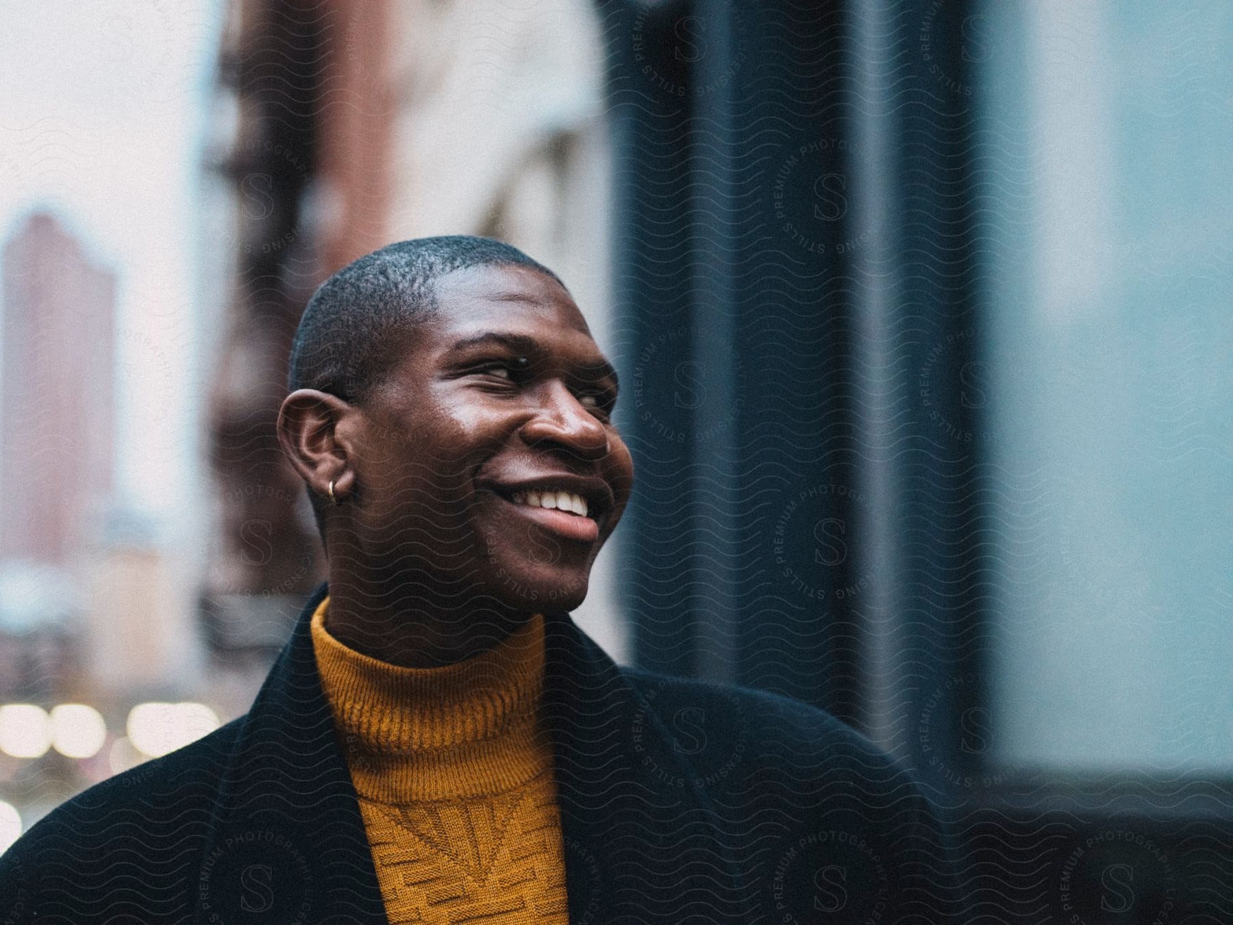 Man standing near downtown buildings has a smile on his face as he turns his head