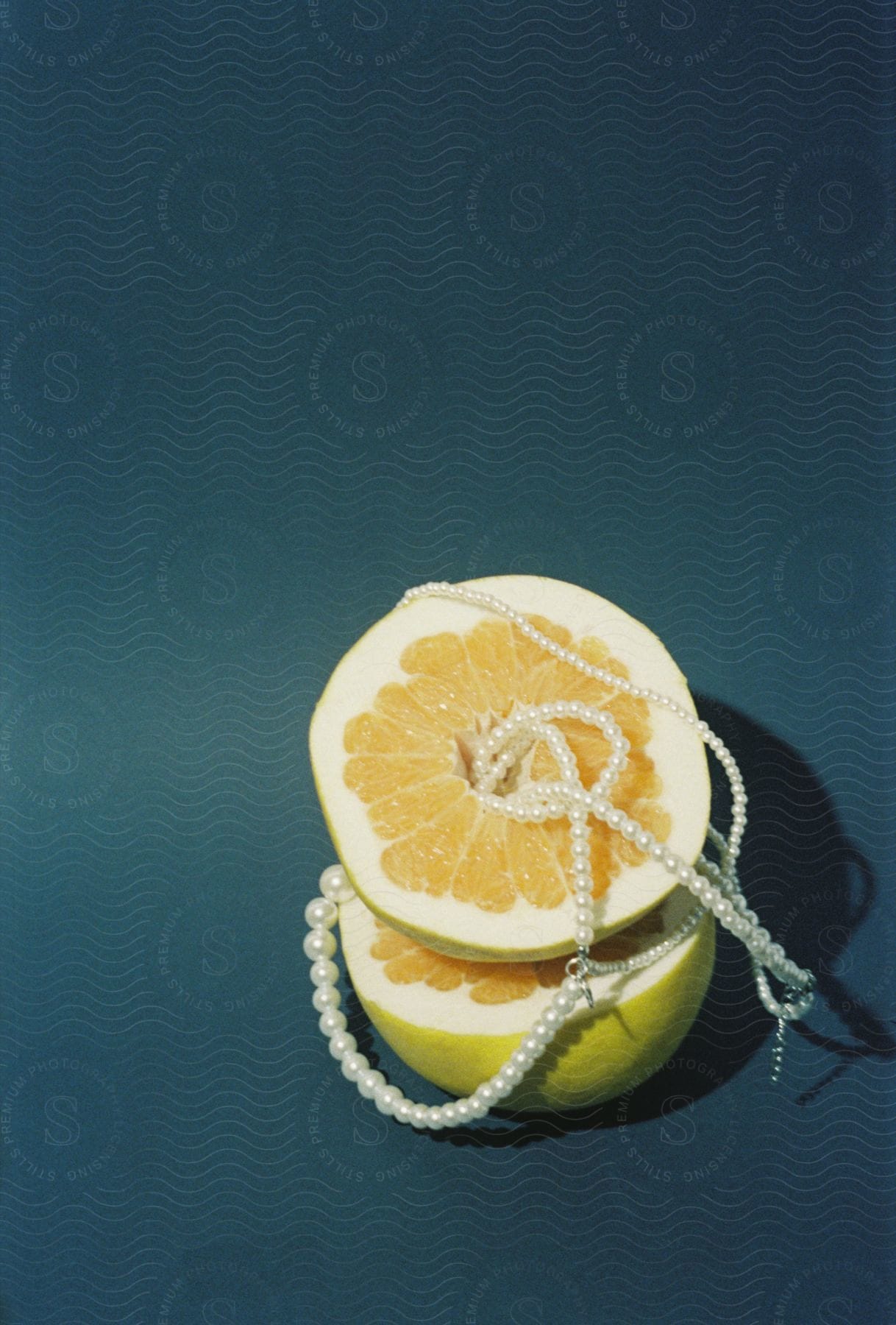 A halved lemon adorned with a glistening pearl necklace draped over it.