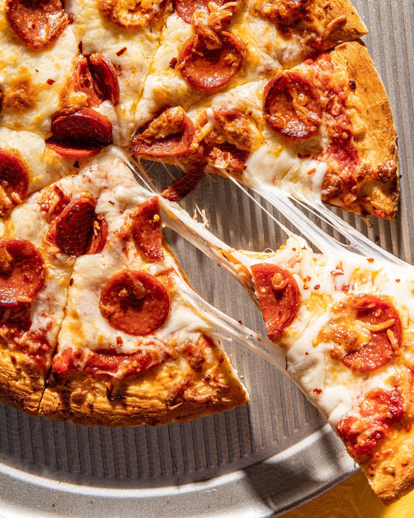 Stock photo of a slice of pepperoni pizza is being pulled as cheese stretches