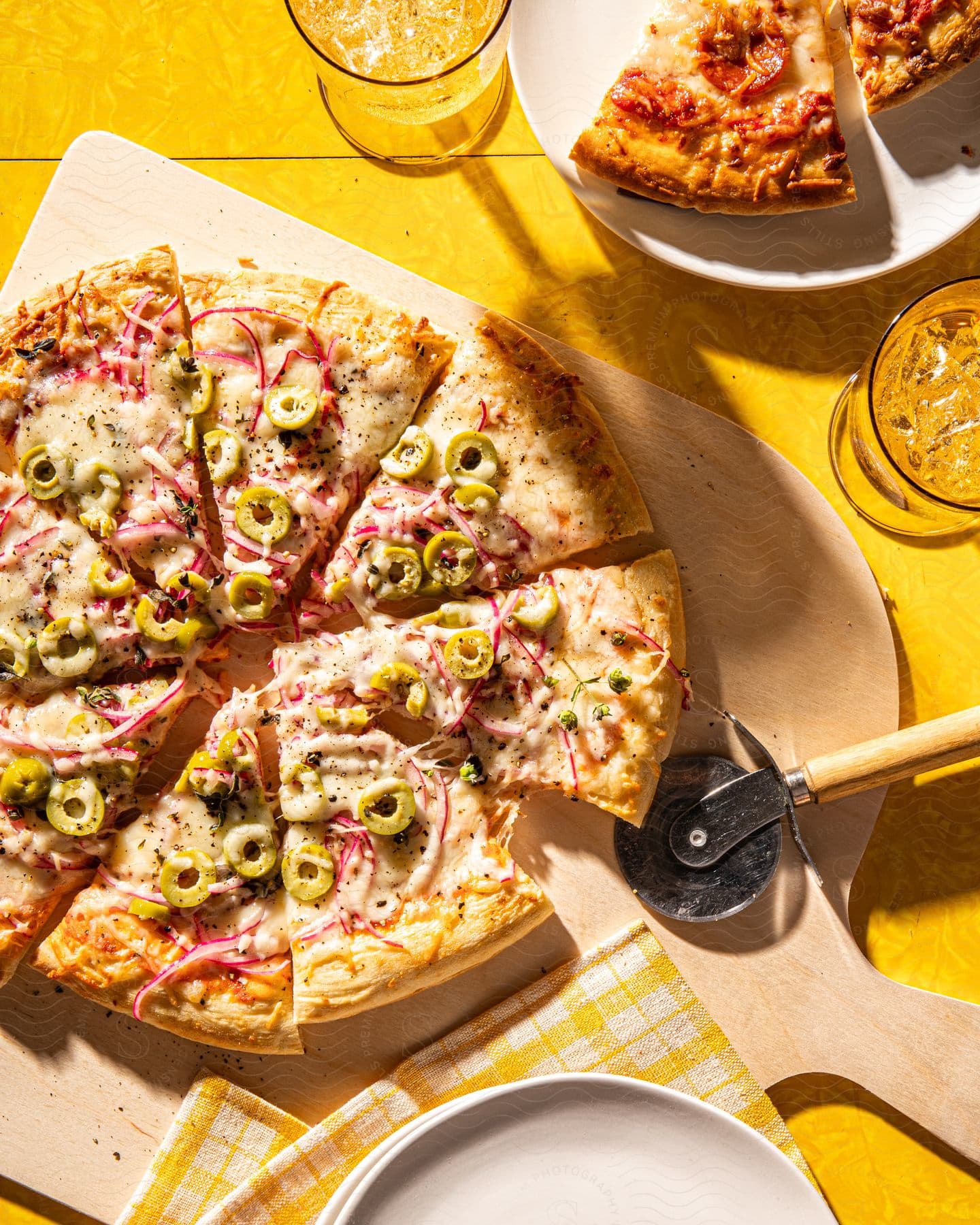 Table with sliced pizzas and glasses with ice