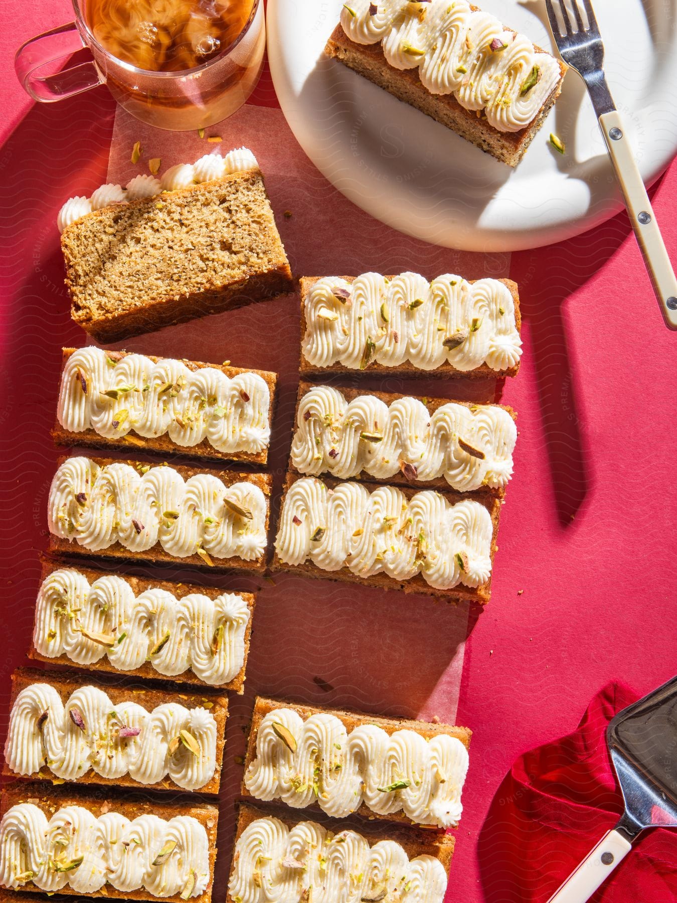 Stock photo of top view of a table with a plate with a slice of cake with cream on top and a glass of tea with ice