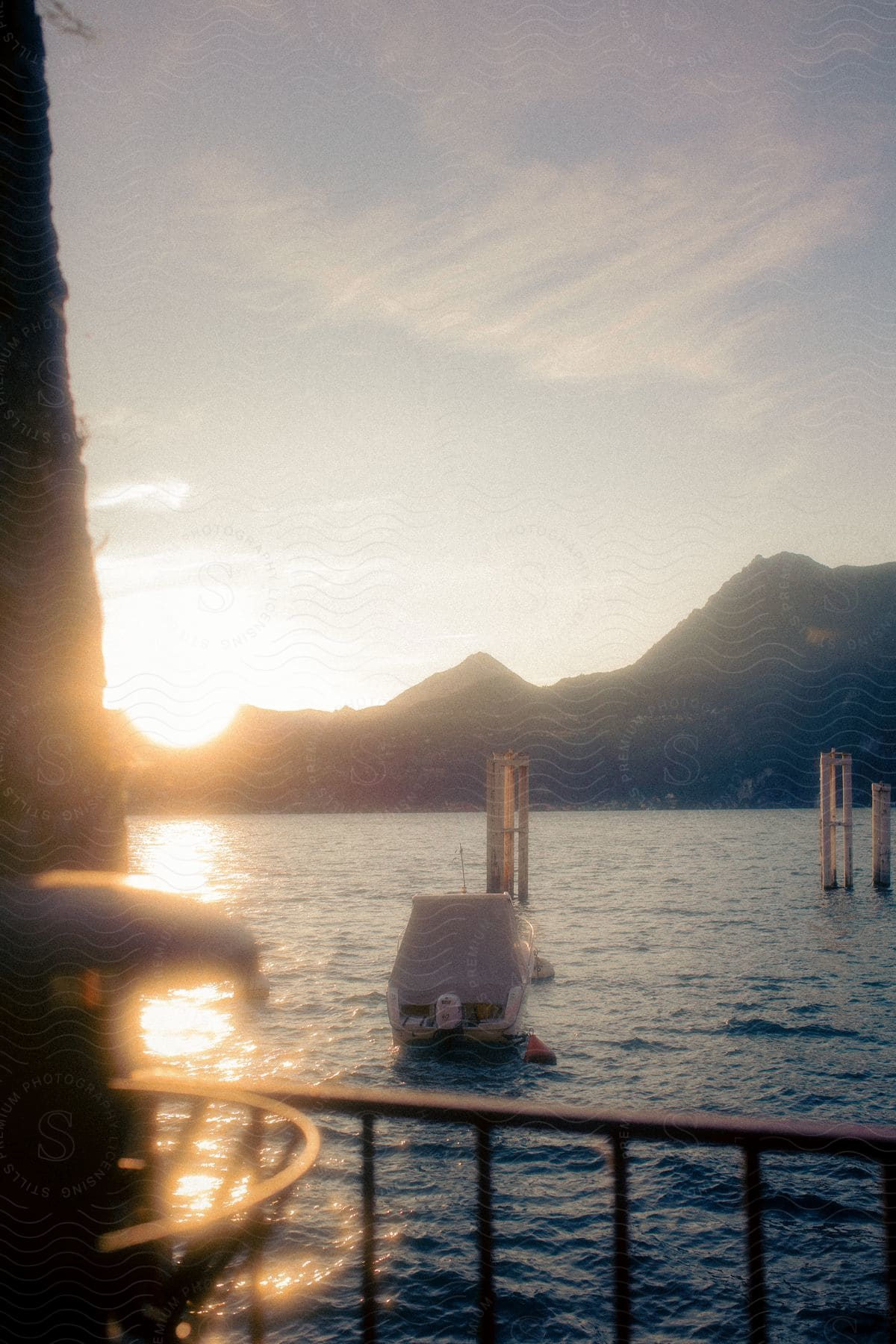 Lake with boat and the silhouette of mountains on the horizon and the reflection of morning sunlight