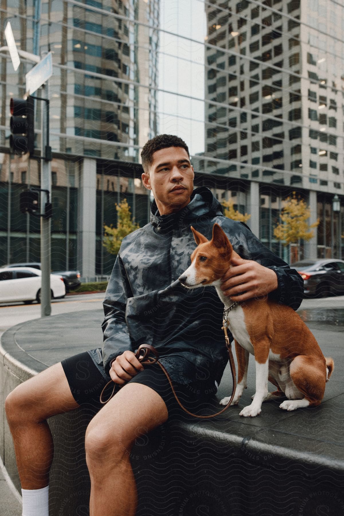 A man sitting on a street bench with a dog in an urban environment.