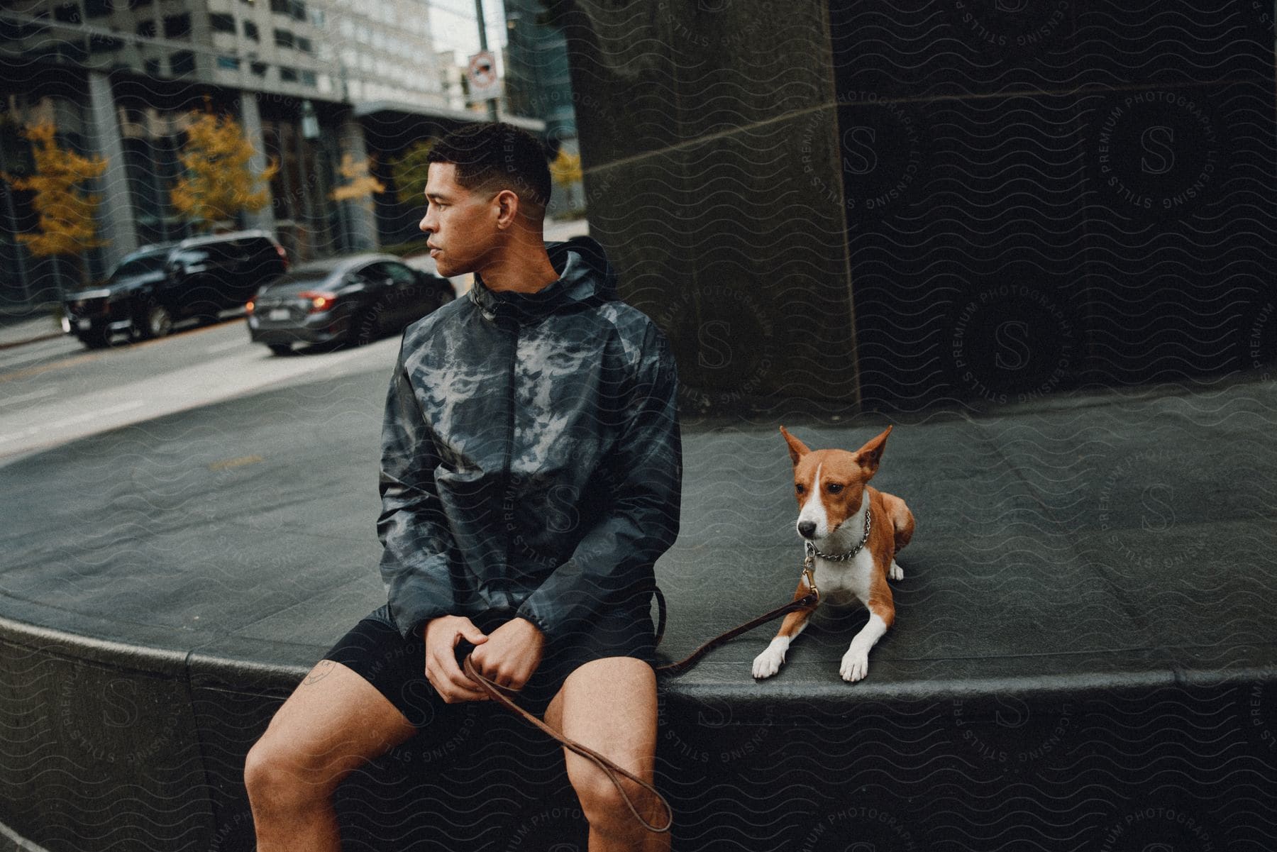 Man sitting in a square with his dog beside him.