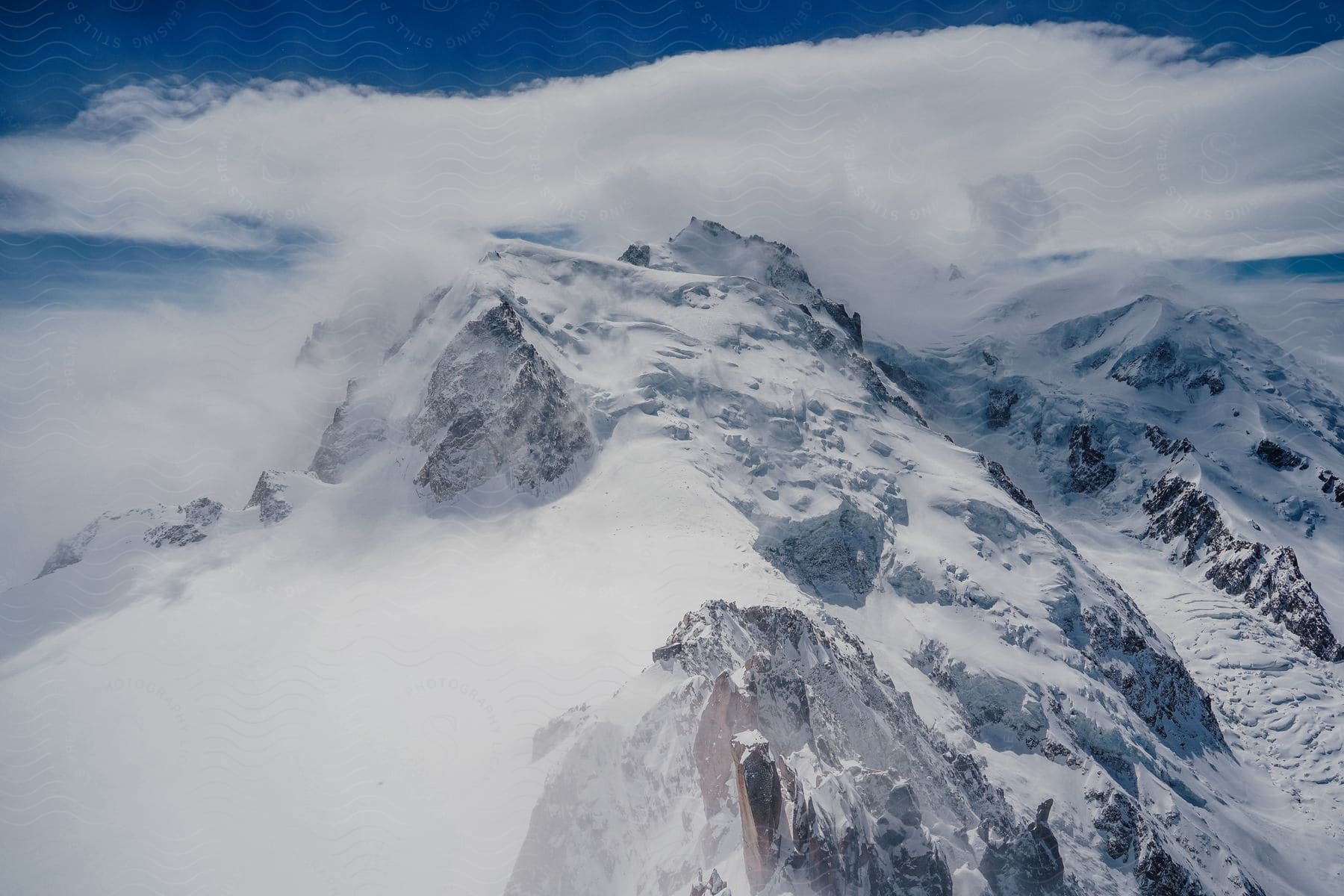 A mountain is covered in snow and ice on a mostly cloudy day.