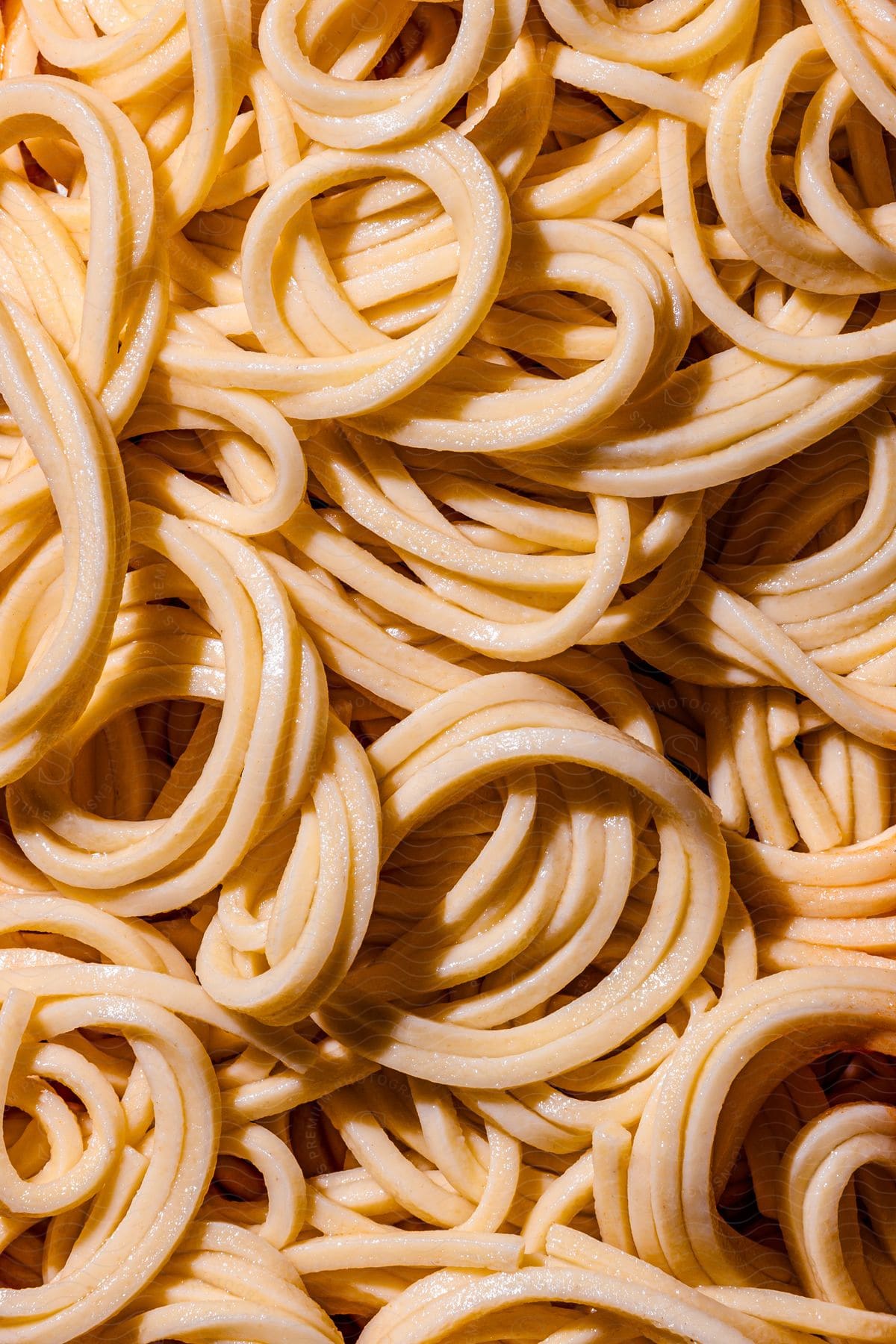 Close-up of cooked spaghetti noodles. The spaghetti strands are pale yellow and appear soft and moist, indicating that they are cooked.