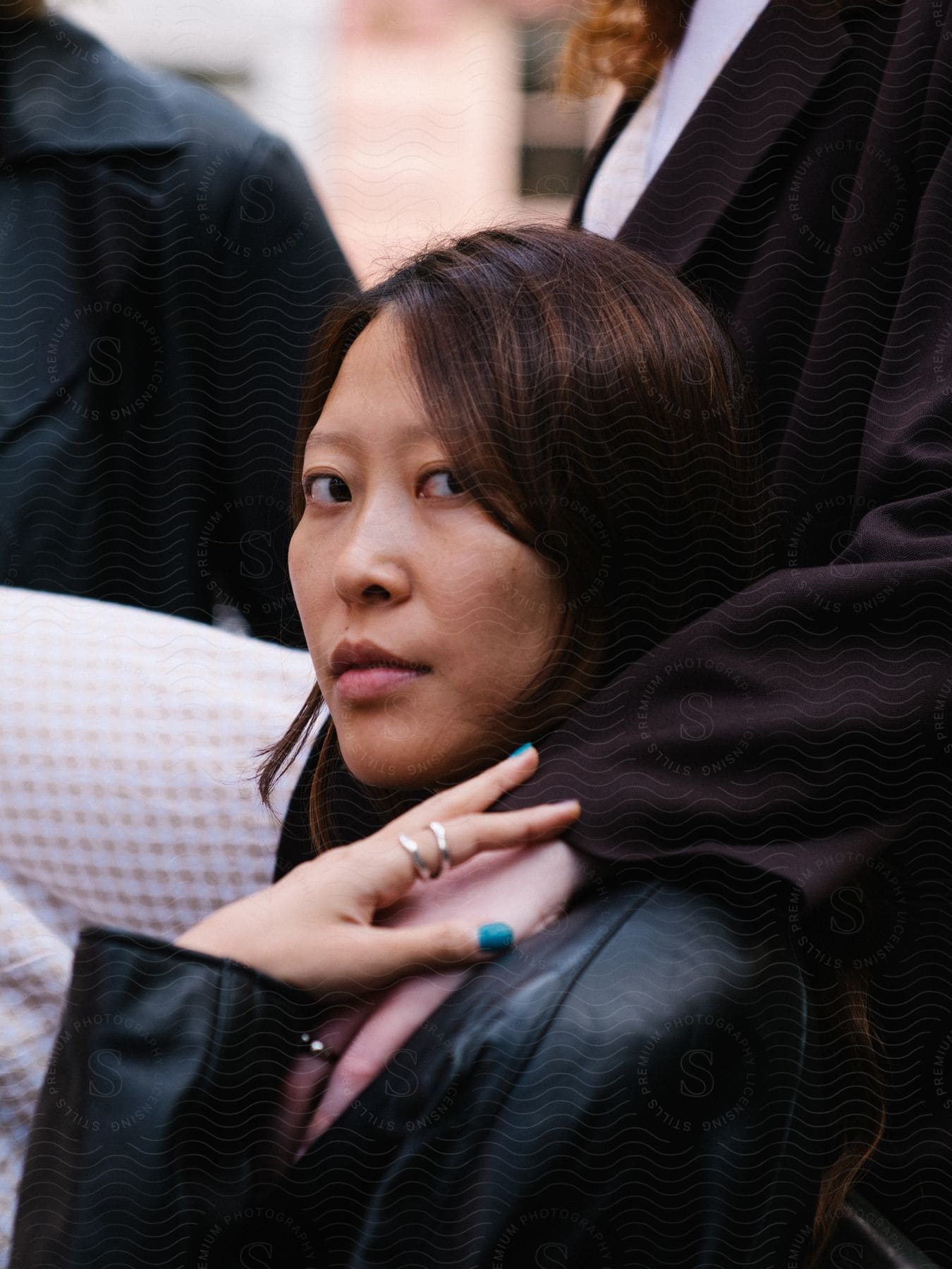 A person wearing a black leather jacket is being hugged by another person wearing a formal black suit and white shirt.