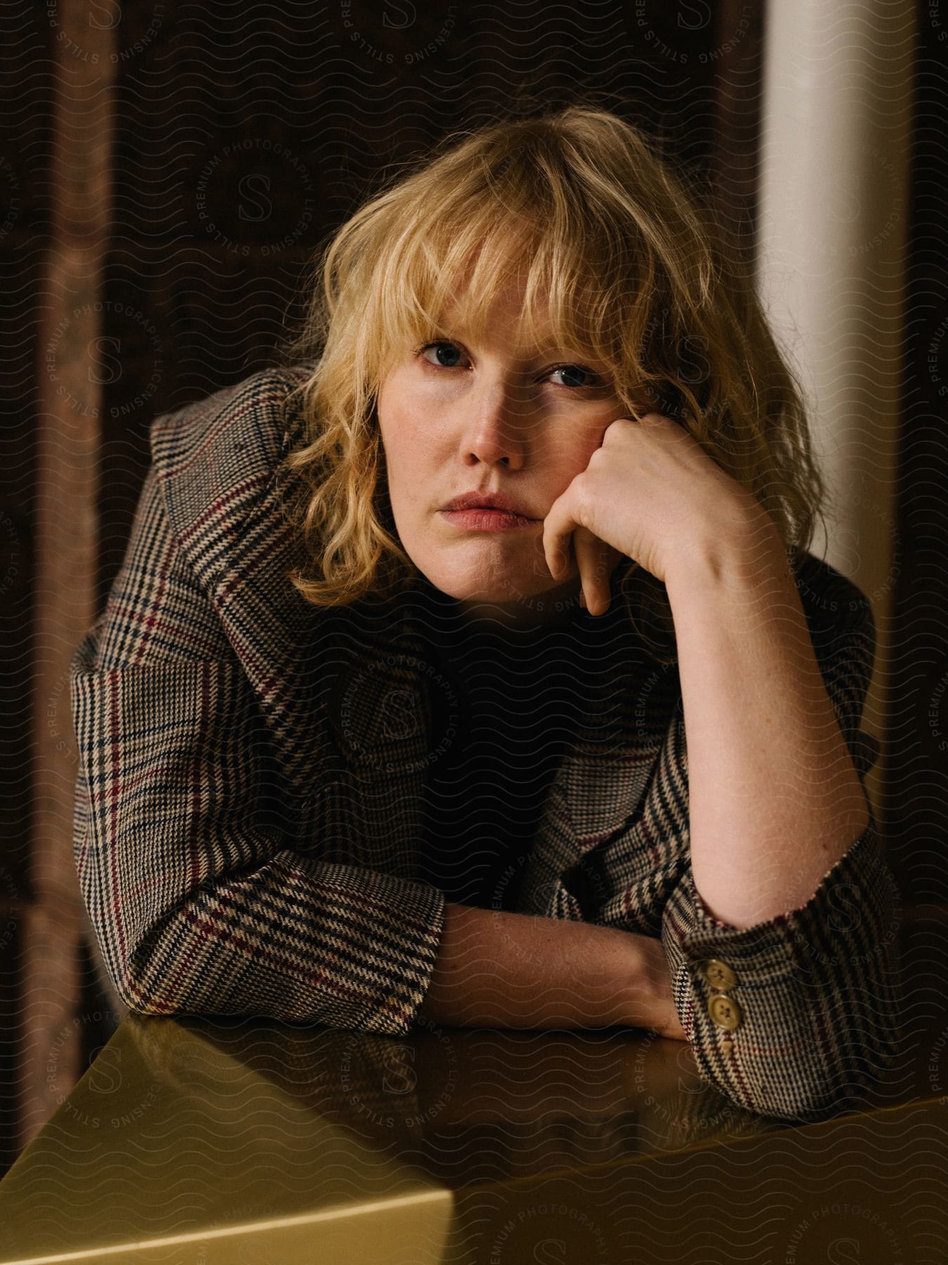 Woman sitting at a table leaning forward with her hand on her cheek