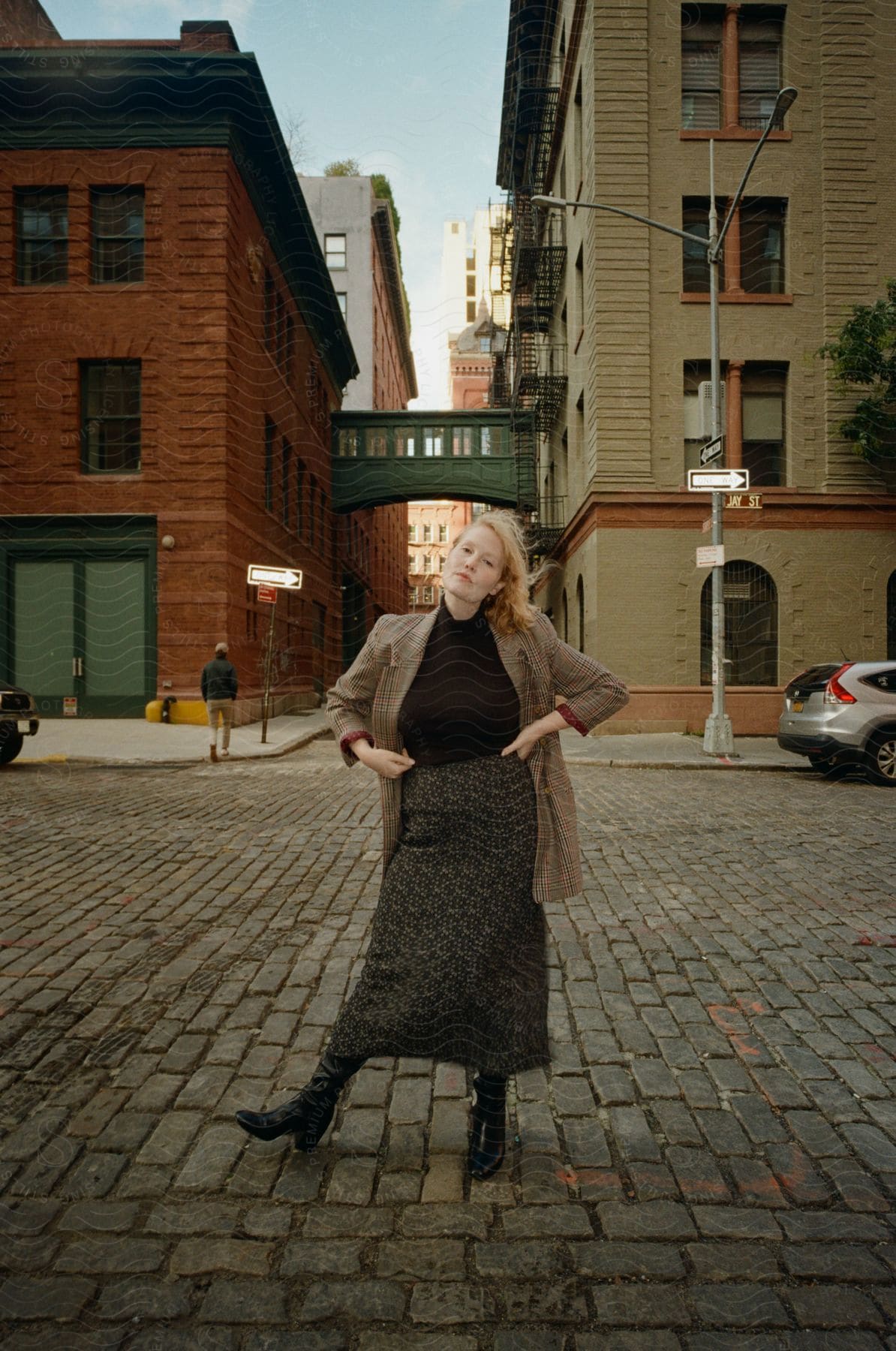 Blonde woman wearing a blazer jacket a black top and a shirt stands on a street in the city