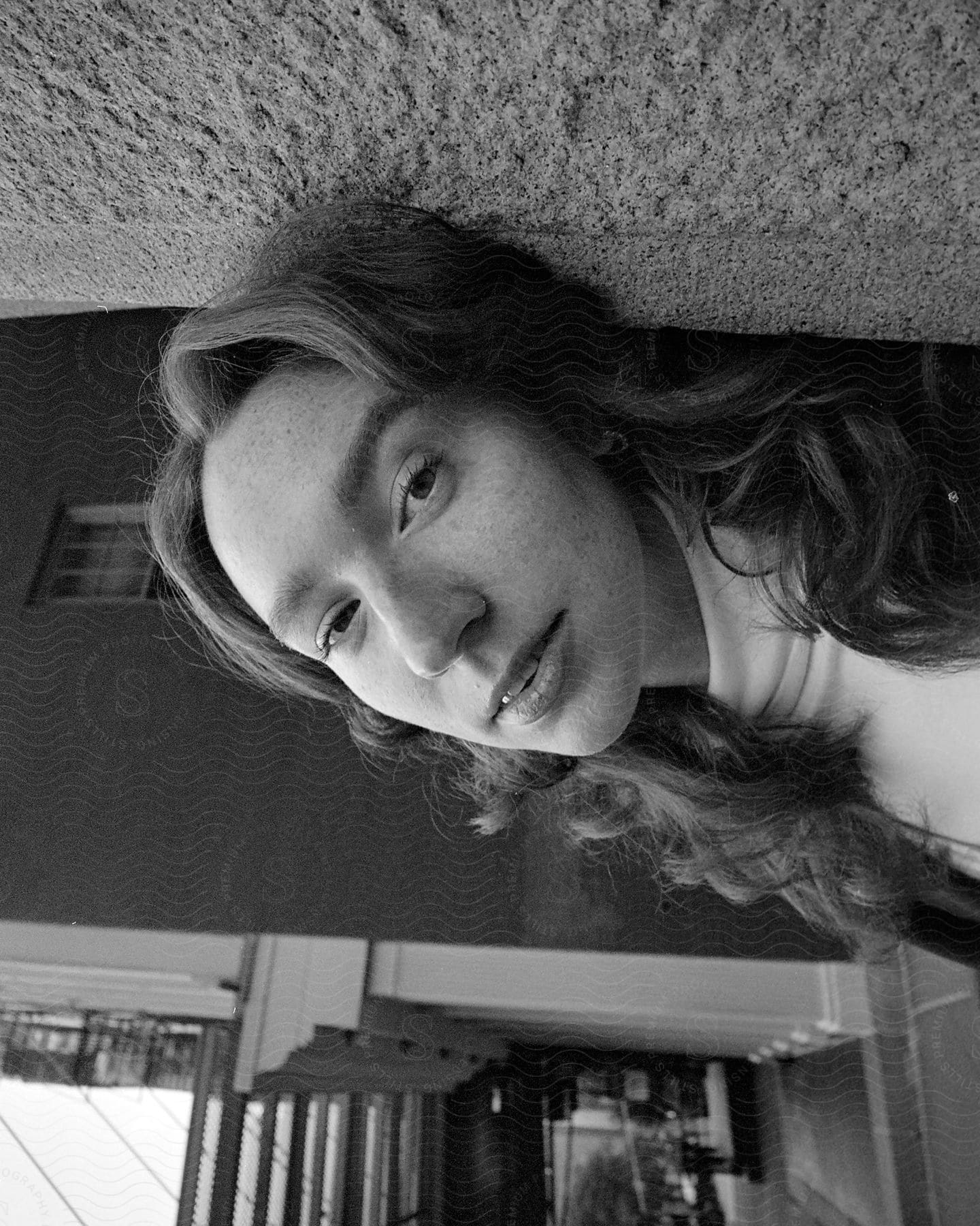 Portrait of a young woman with long hair leaning against a wall in an urban city