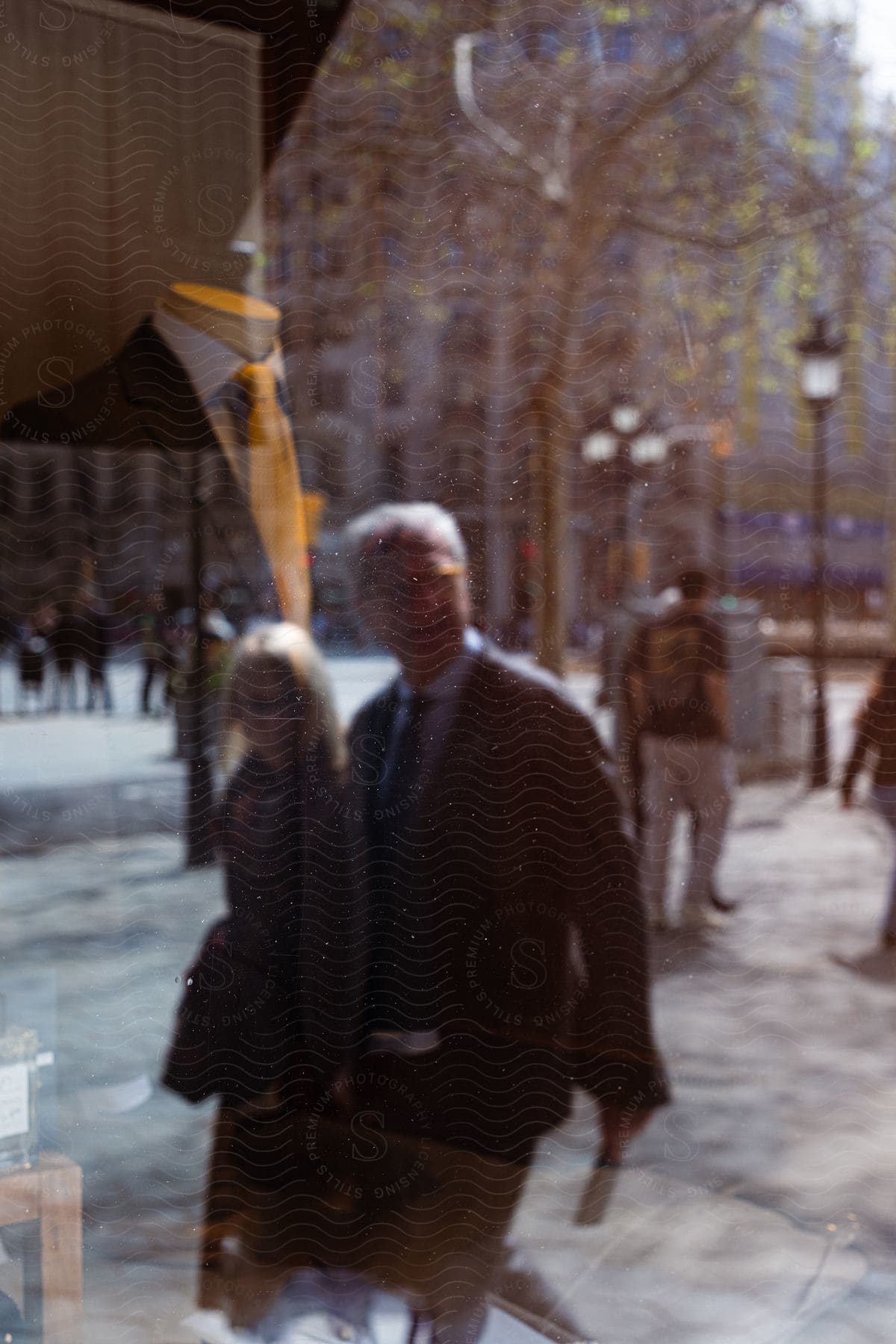 A couple walking past a store window displaying a mannequin dressed in formal attire in the city