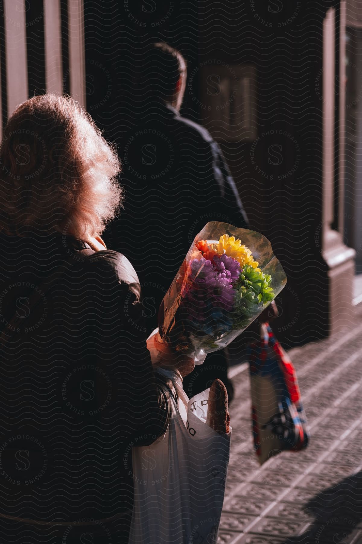 A back clip of a man holding an arm pack and a lady holding a flower and an arm pack