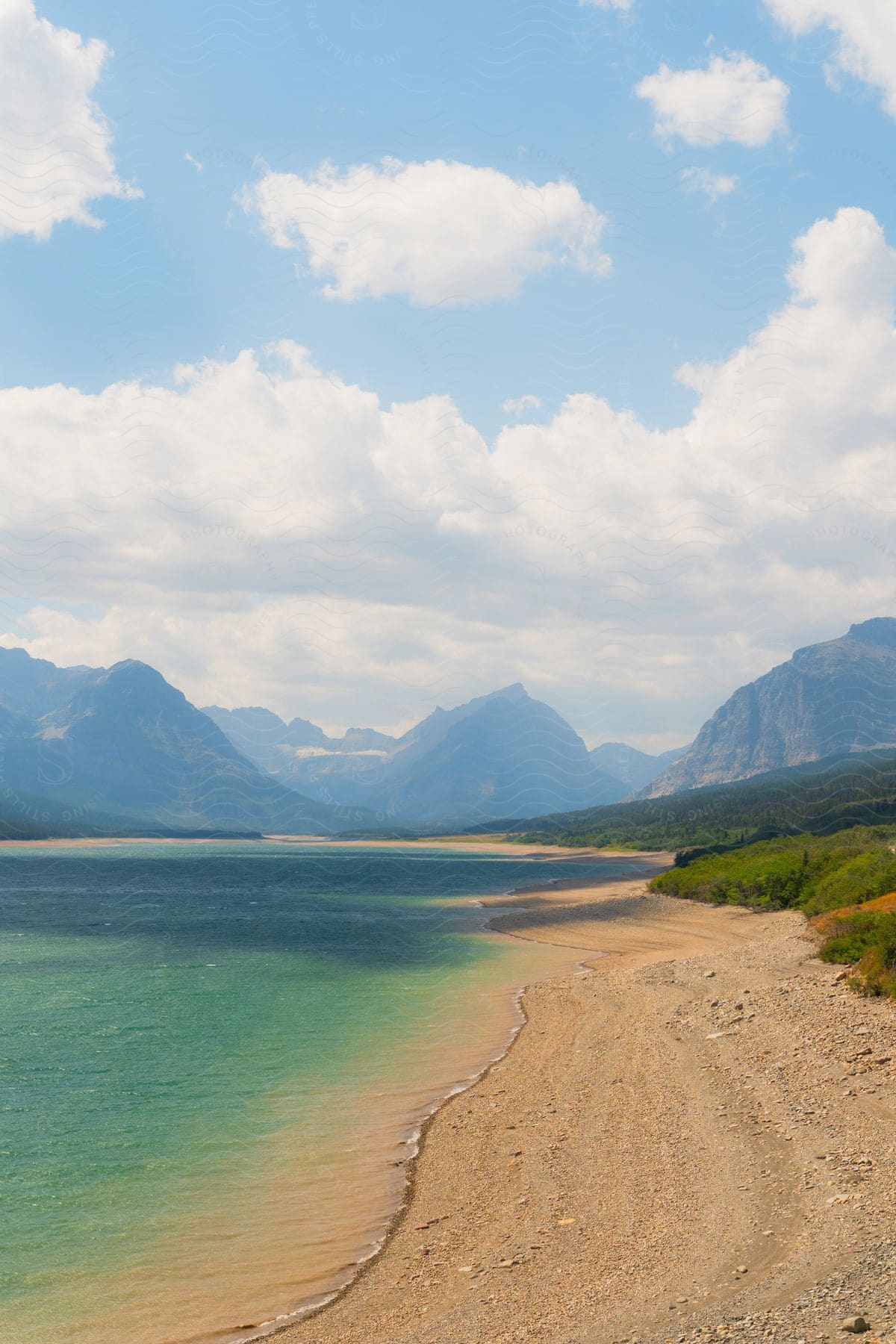 A highland on the beachside is surrounded by mountains in the surrounding environment.