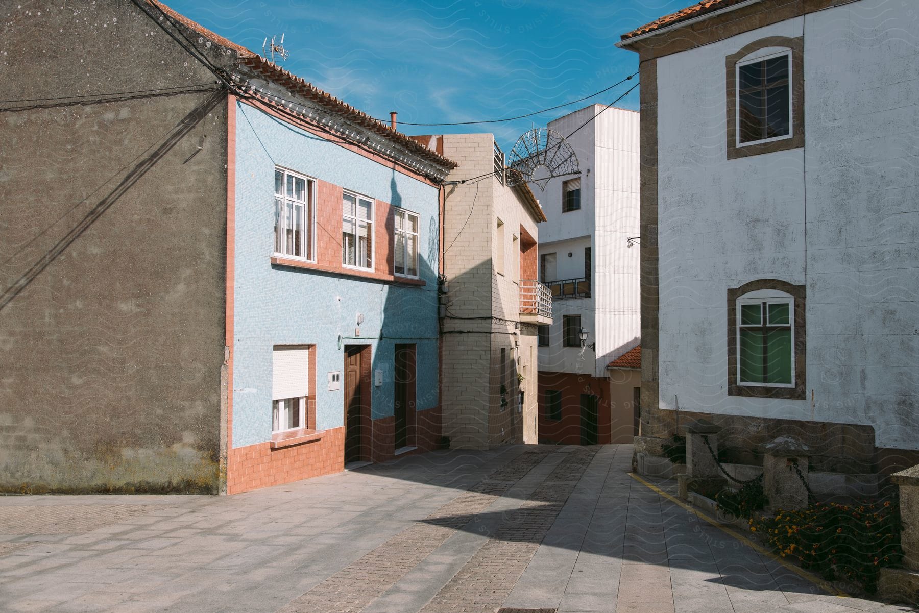 A group of houses sit close together with a concrete alley between them on a sunny day.