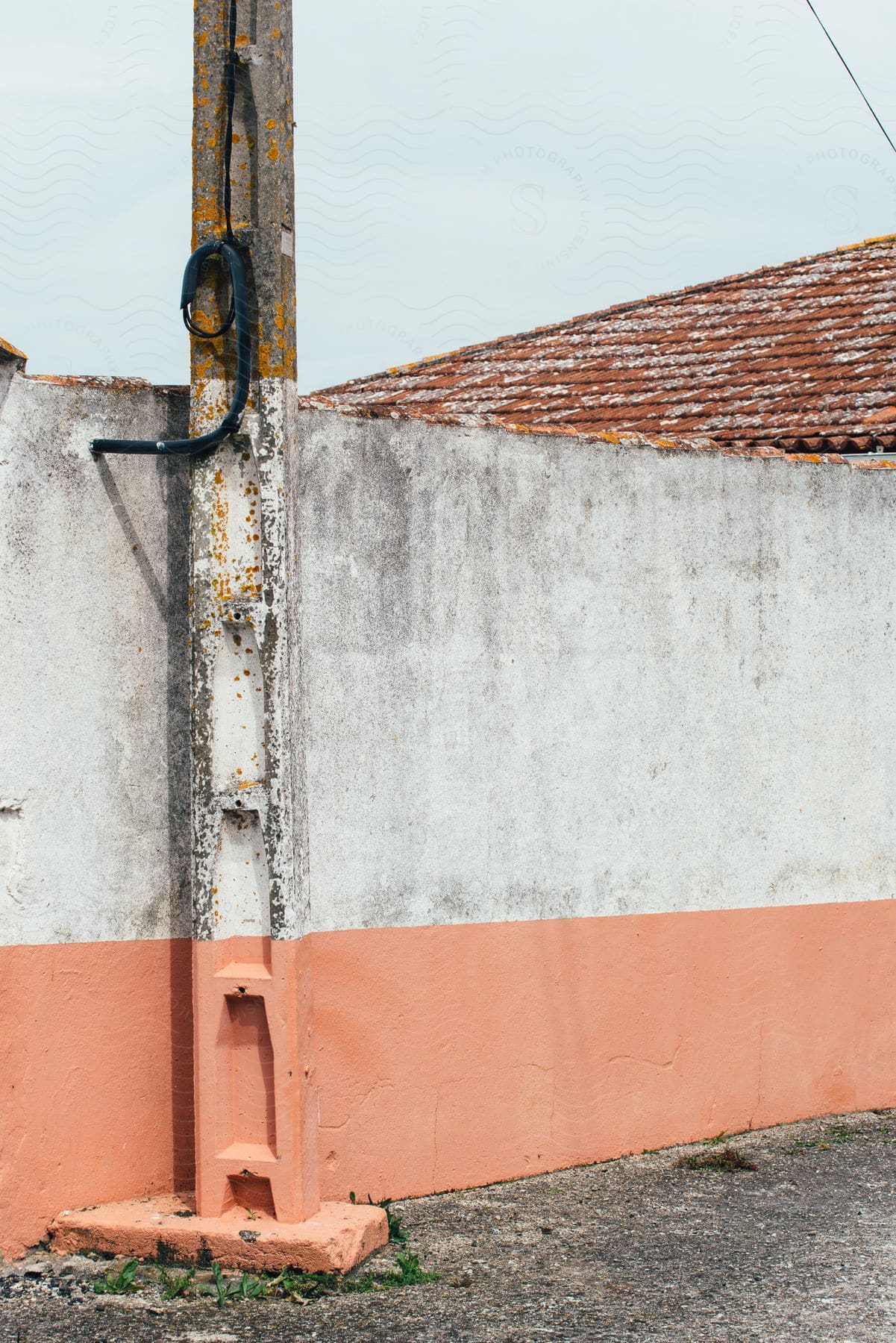 A wall where the bottom part is painted pink and the top part is white and on the left side there is a building painted in the same place