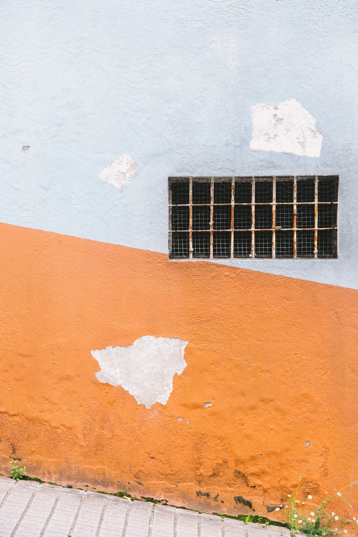 Dilapidated building on a hill with a window covered with bars and inside fence