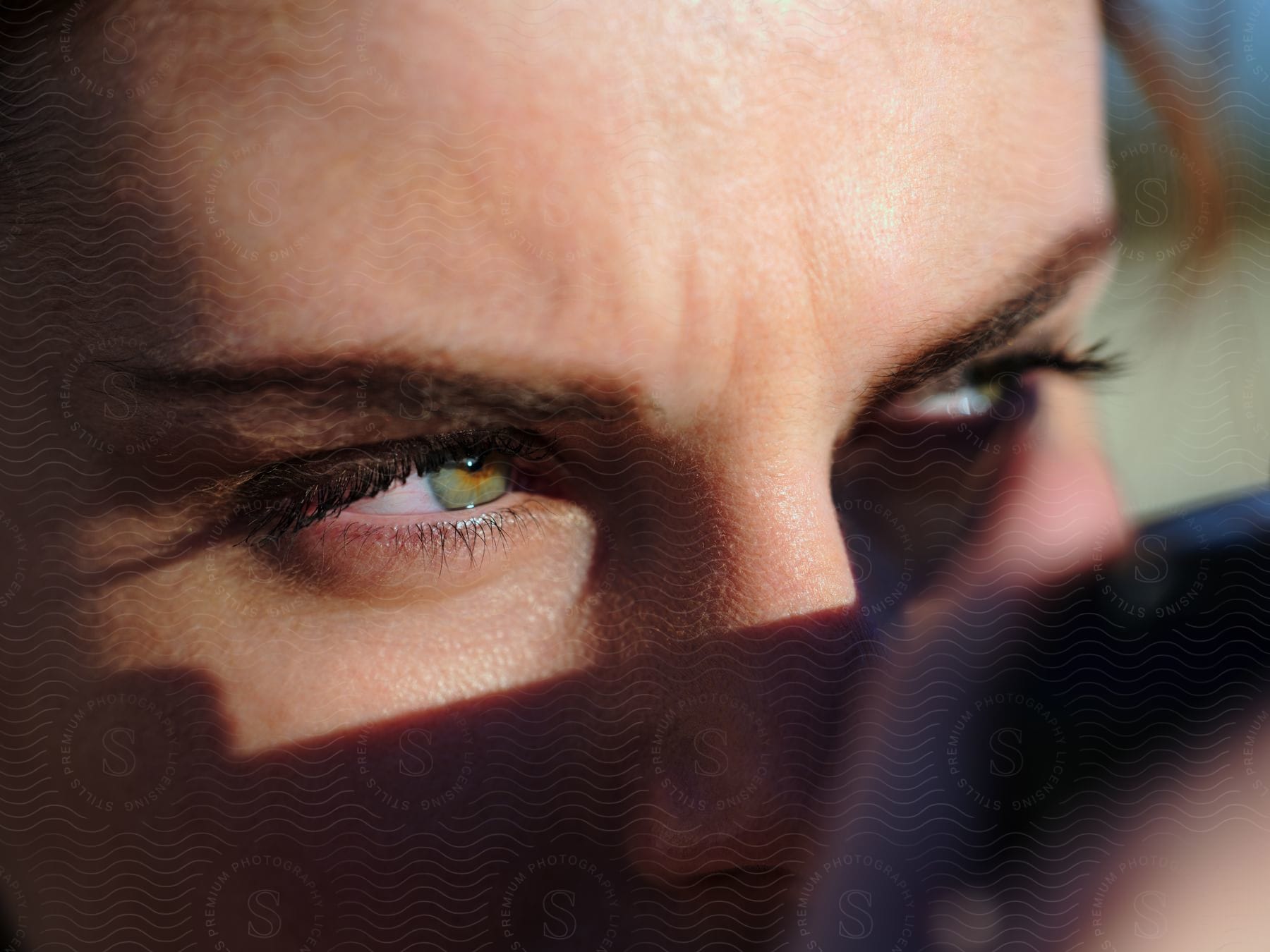 Woman with green eyes and eyelashes looks away.