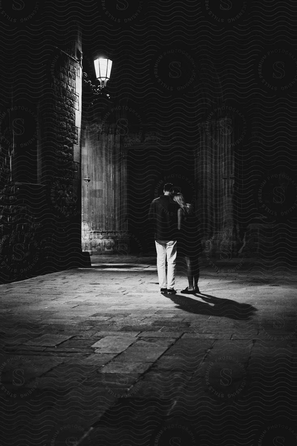 Couple hugging each other walking in an alley in a dimly lit environment.