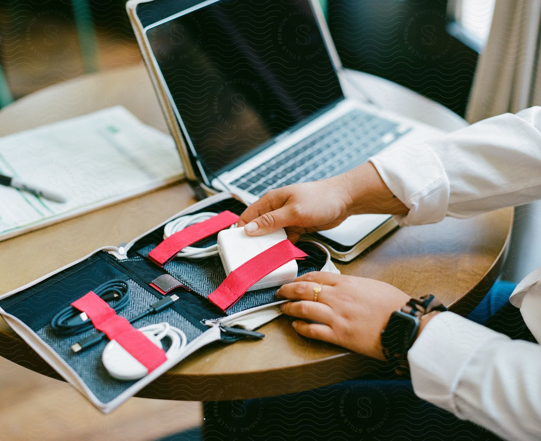 Person sitting at a table with a laptop computer as they take accessories from a small case