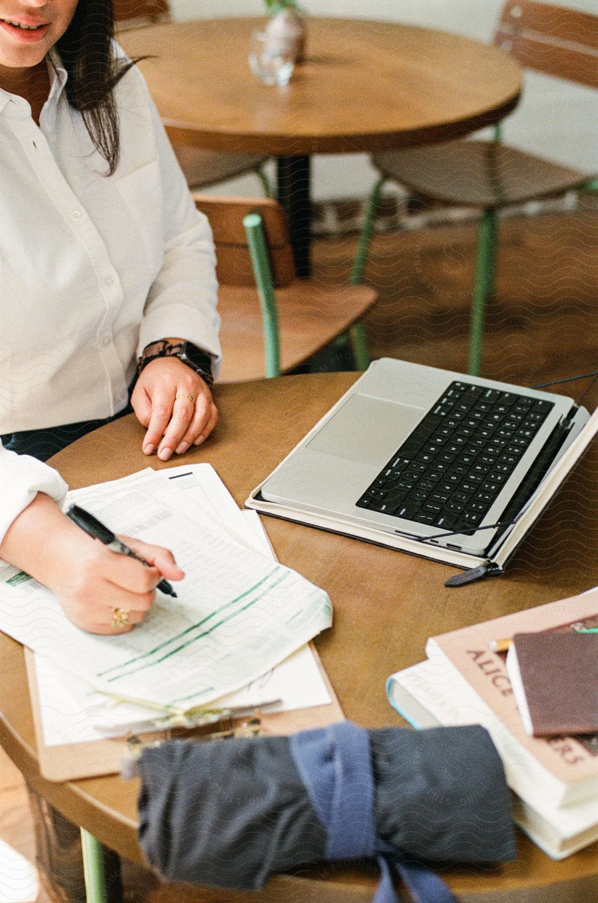 Woman sitting at a table with a laptop computer writes on paper