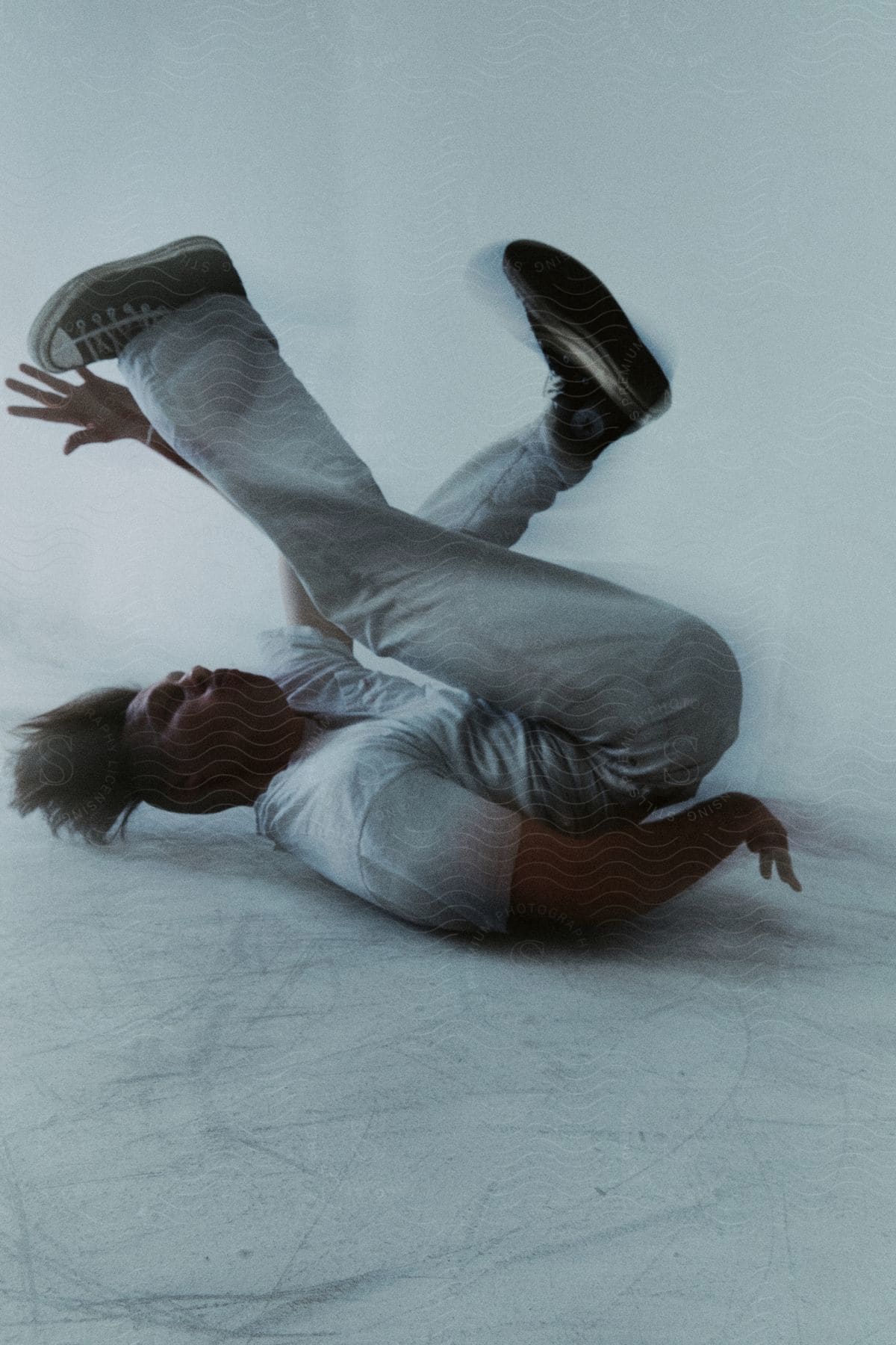 Stock photo of man lying with his back on the floor in breakdancing movement in an indoor room with white walls