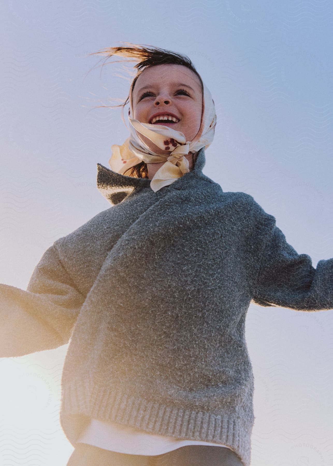 Stock photo of little girl with a cloth on her head and a woolen blouse smiling