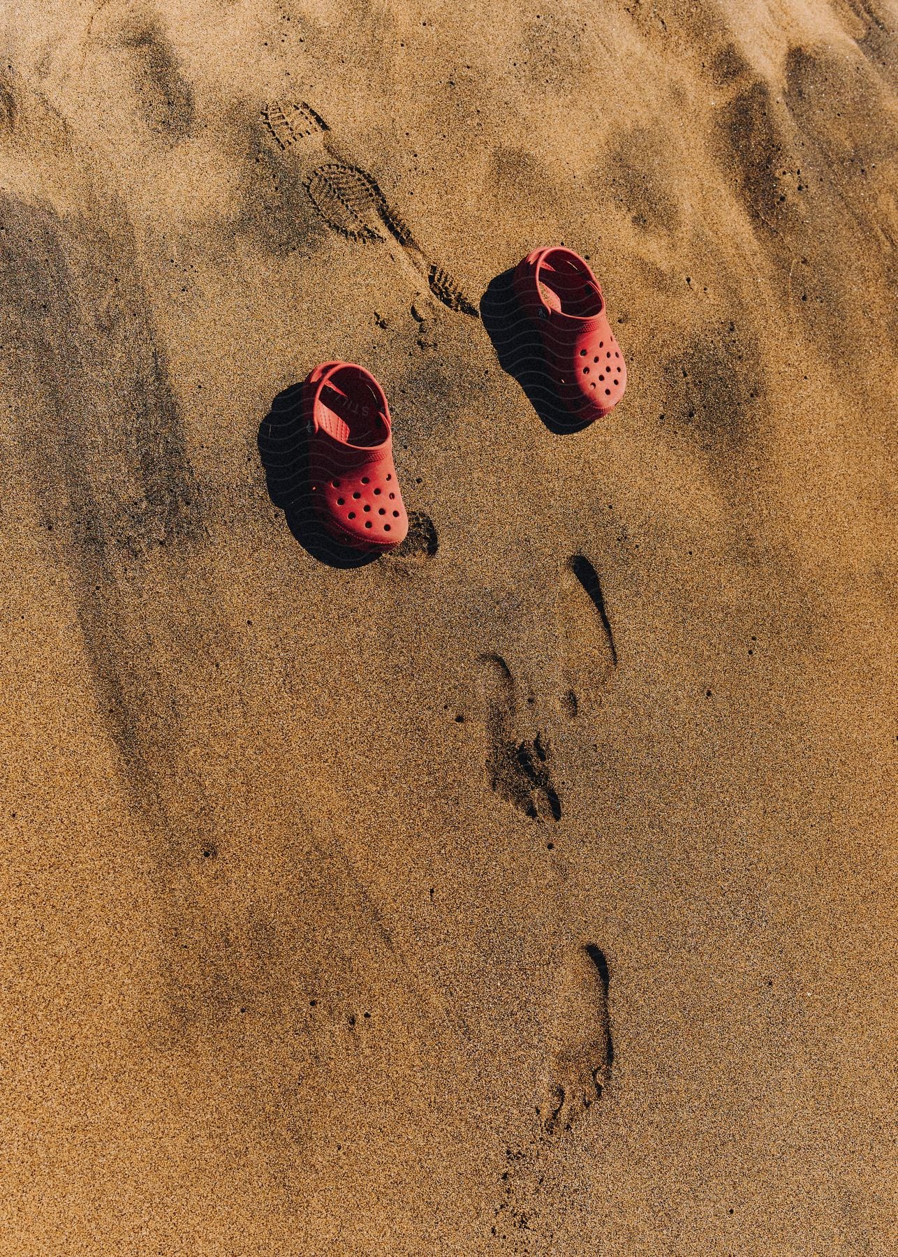 A clip of a pair of red slippers on the beach sand