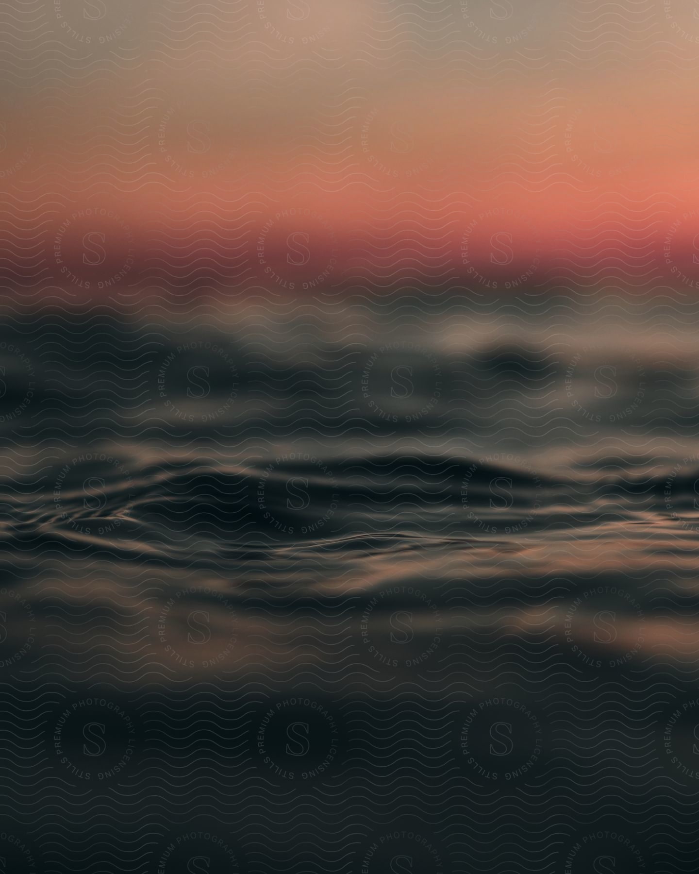 A serene view of gentle waves on the water under a soft and colorful sunset.