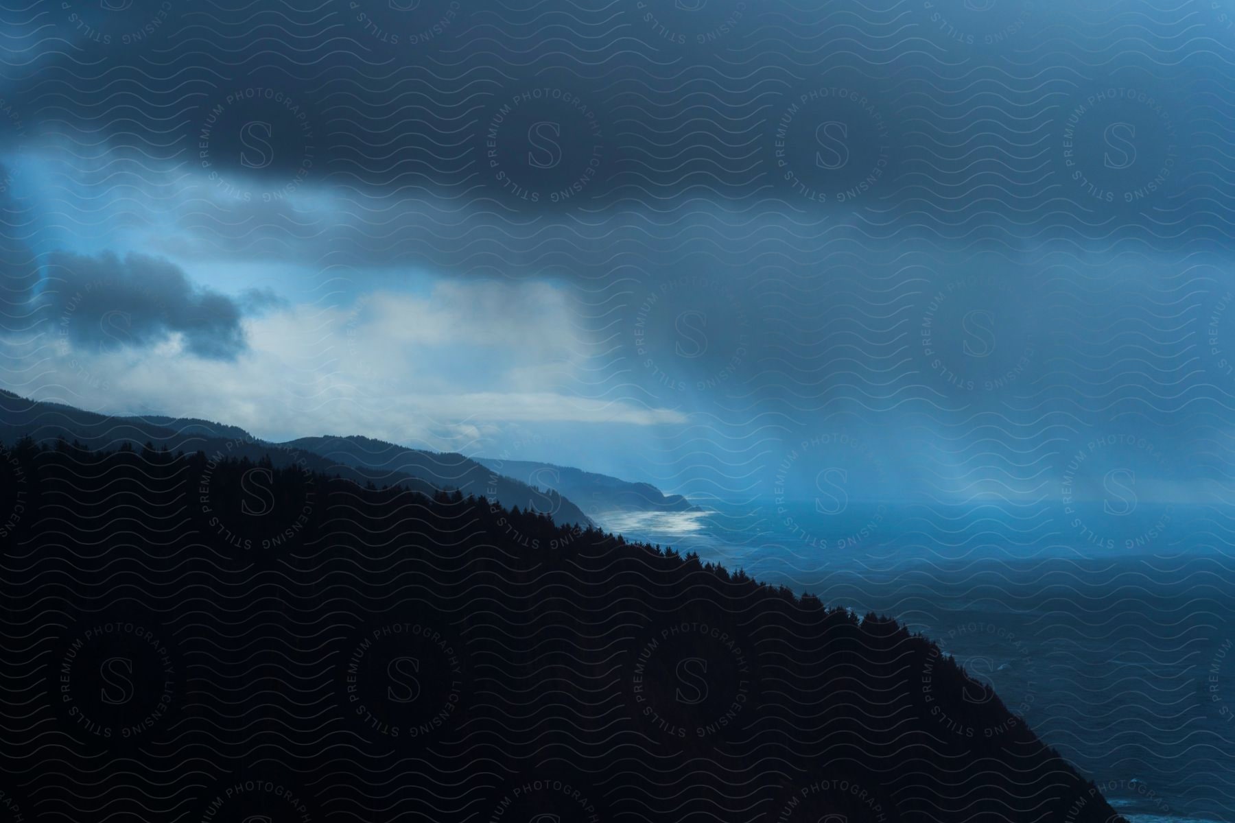 A rainstorm over the ocean near a mountainous coastline