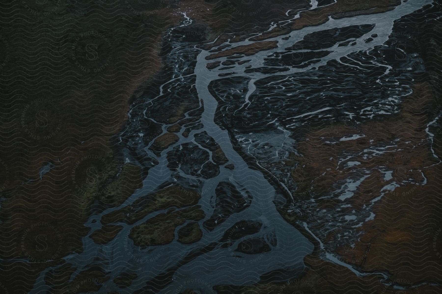 An aerial view at night reveals a rural river, its many channels like shimmering veins winding through the dark landscape.