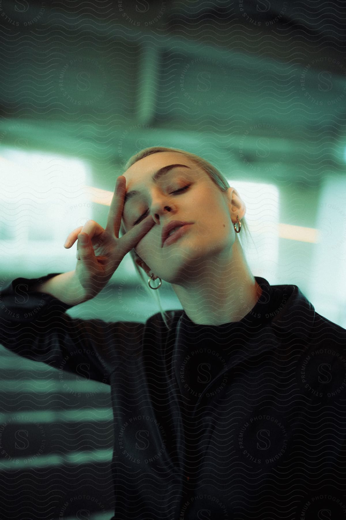 A young teenage girl making the scissor gesture with her right hand while holding it near her face.