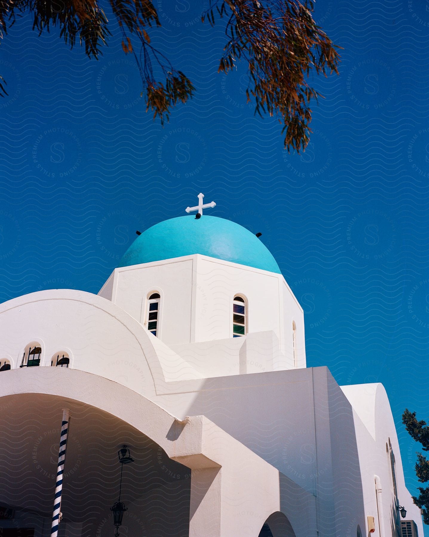 Church with traditional architecture of the Greek islands with whitewashed walls and a blue dome with a cross and under a clear sky.