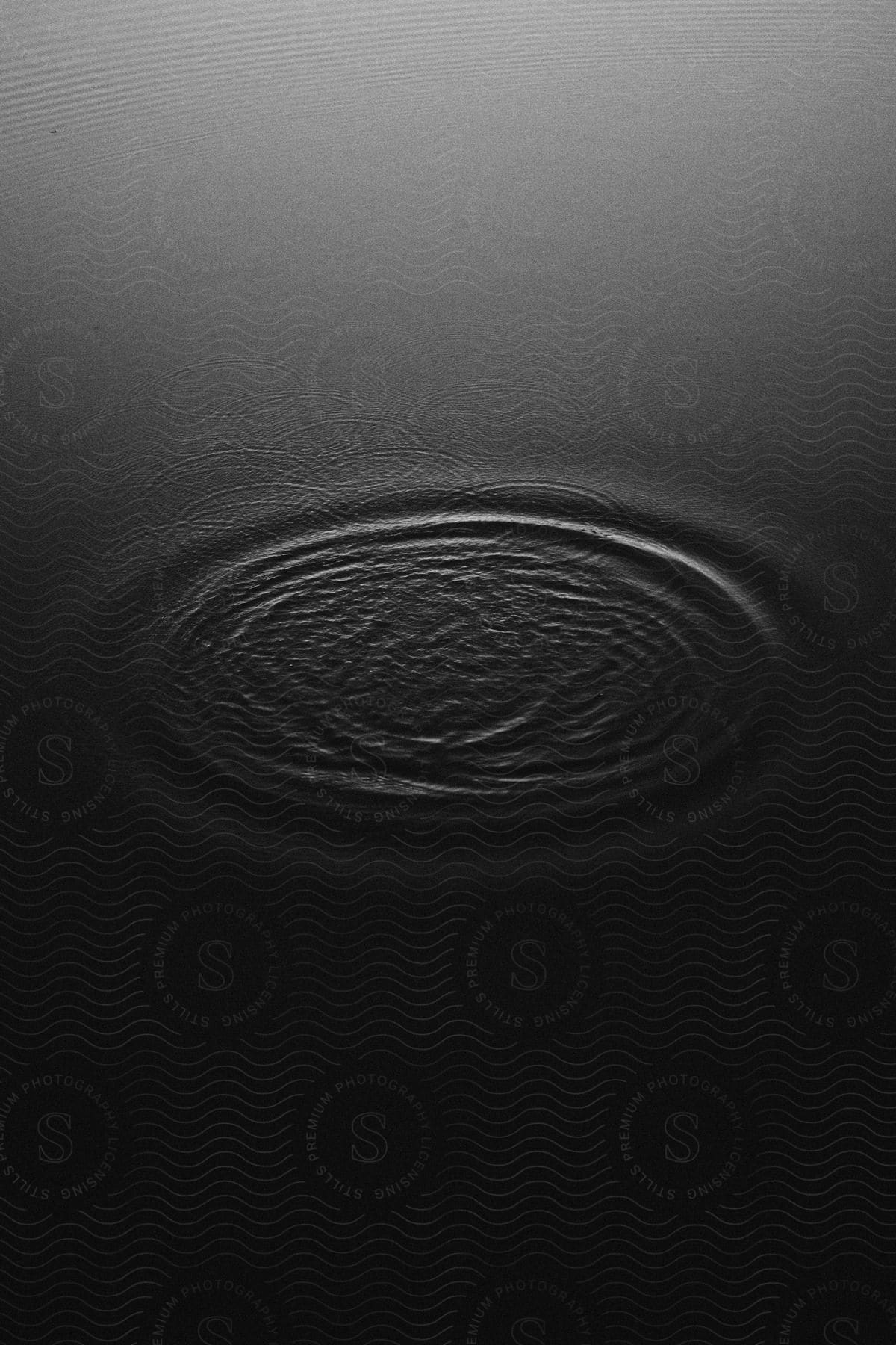 Water with ripples emanating from a central point creating a pattern of abstract concentric circles.