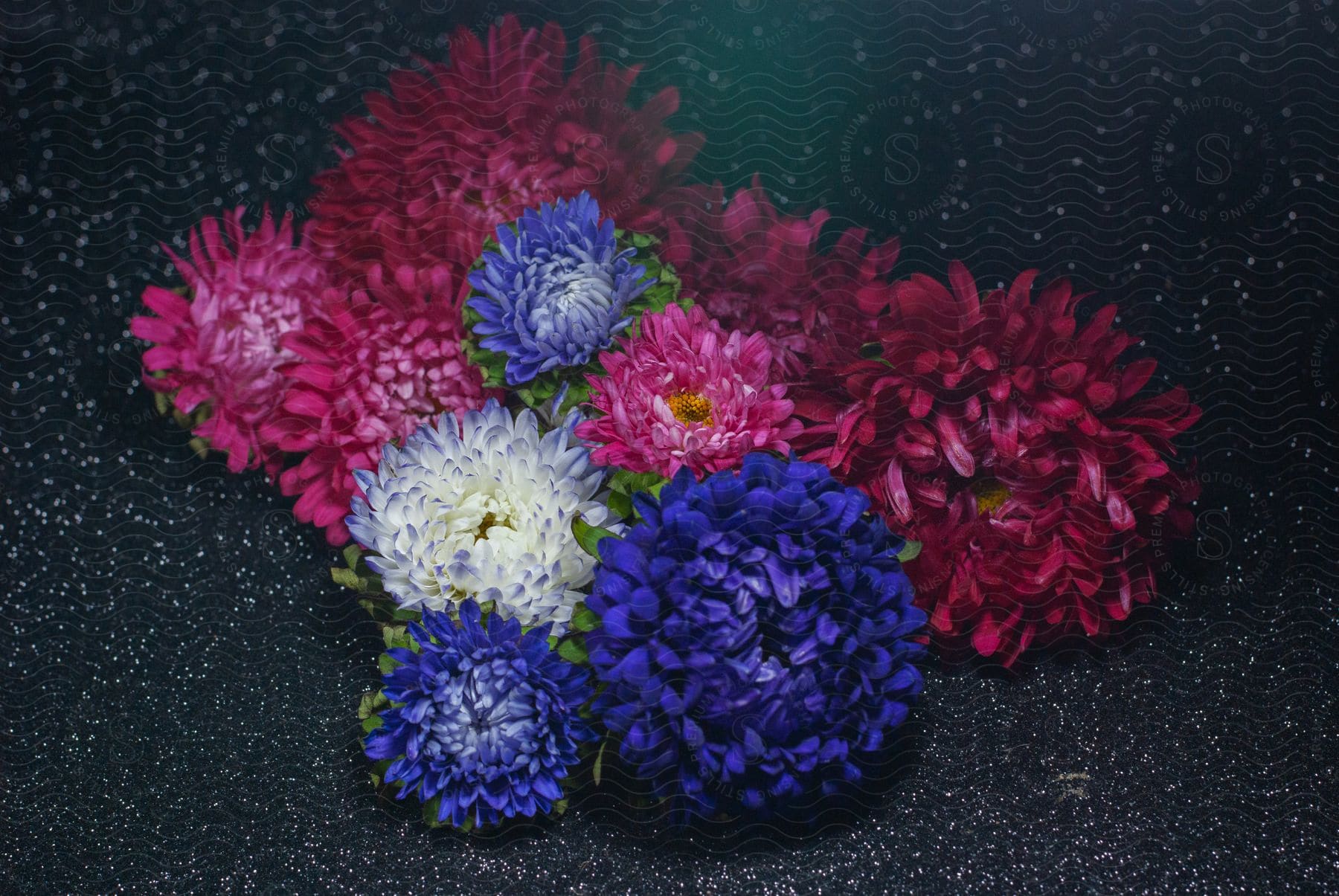 A vibrant bouquet of colorful flowers sits on black sand