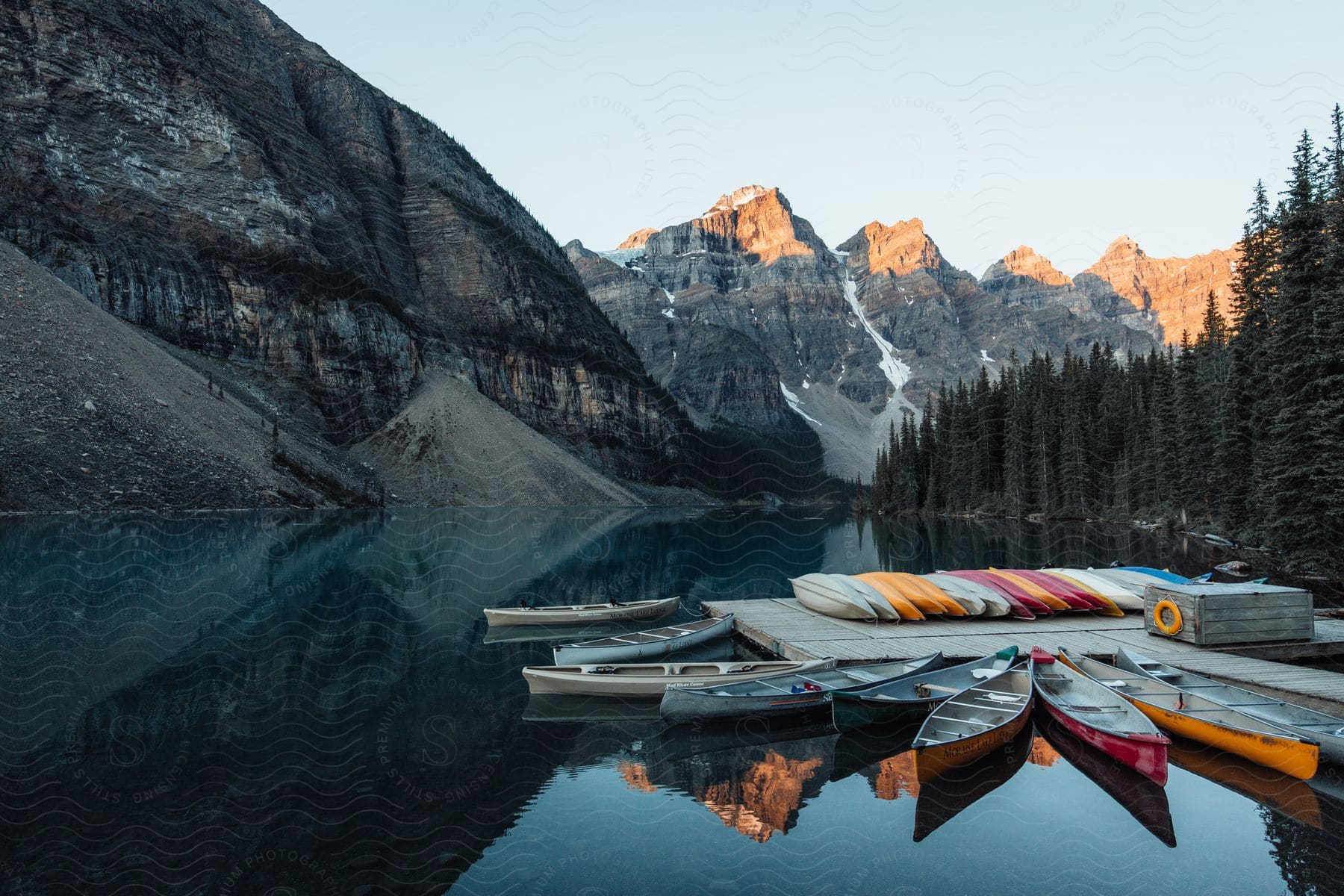 multiple boats are parked at a dock near the mountainous coast