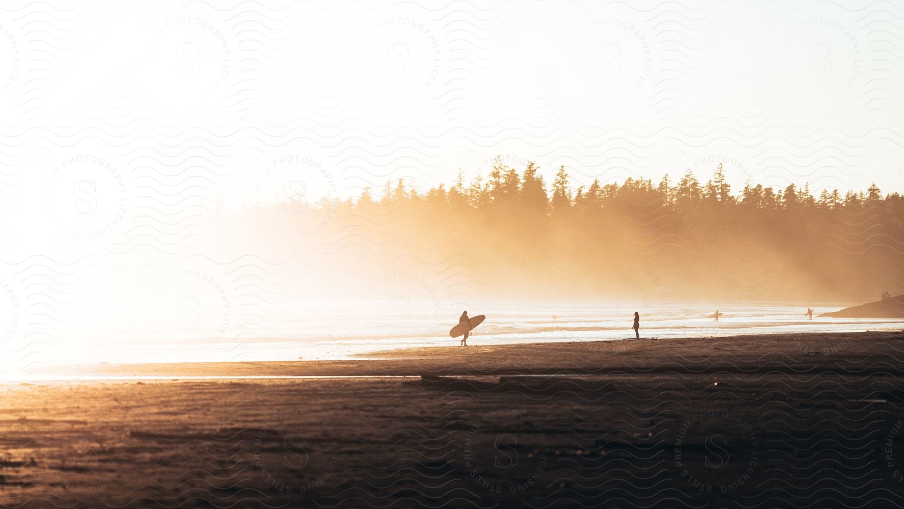 A person holding a surfboard on the beach near some water