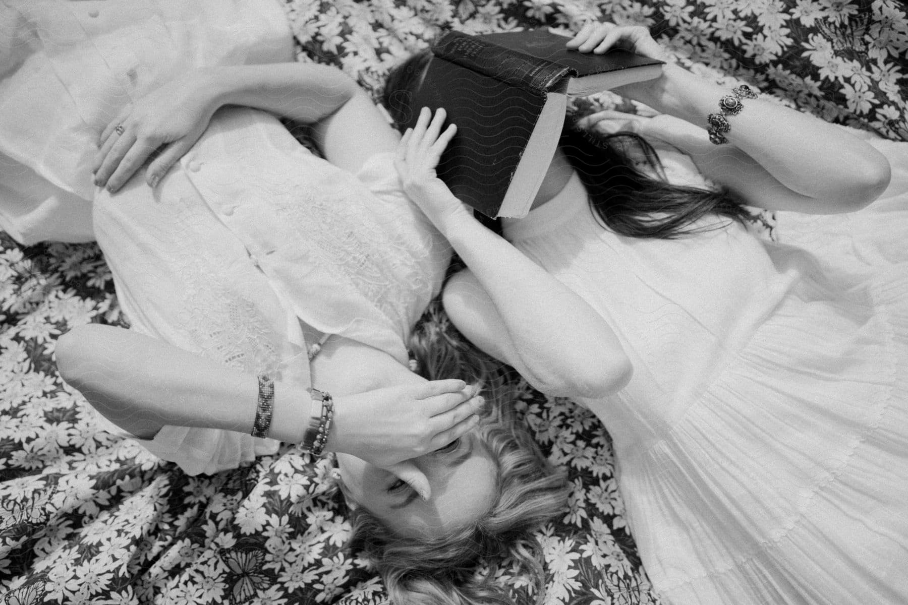 Two woman lie on a floor posing for a camera