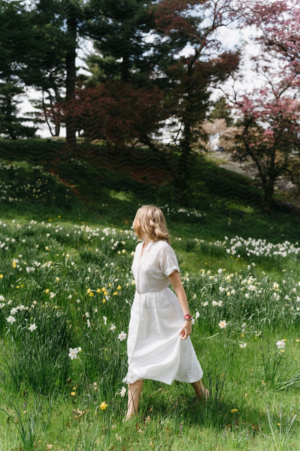 a woman in white walks through a field of flowers.