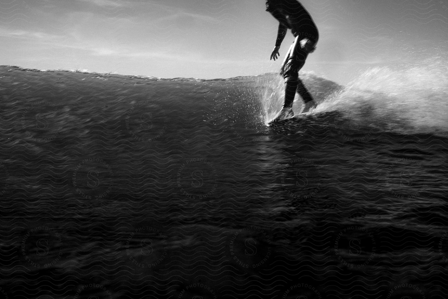 Legs of a person on the corner of the board surfing a wave