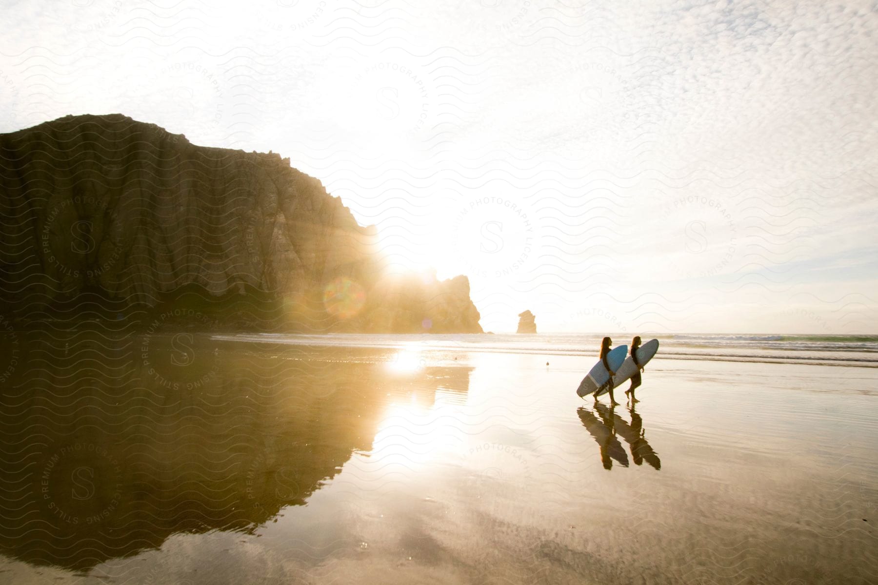 A view of two women walking with surfboards on the beach